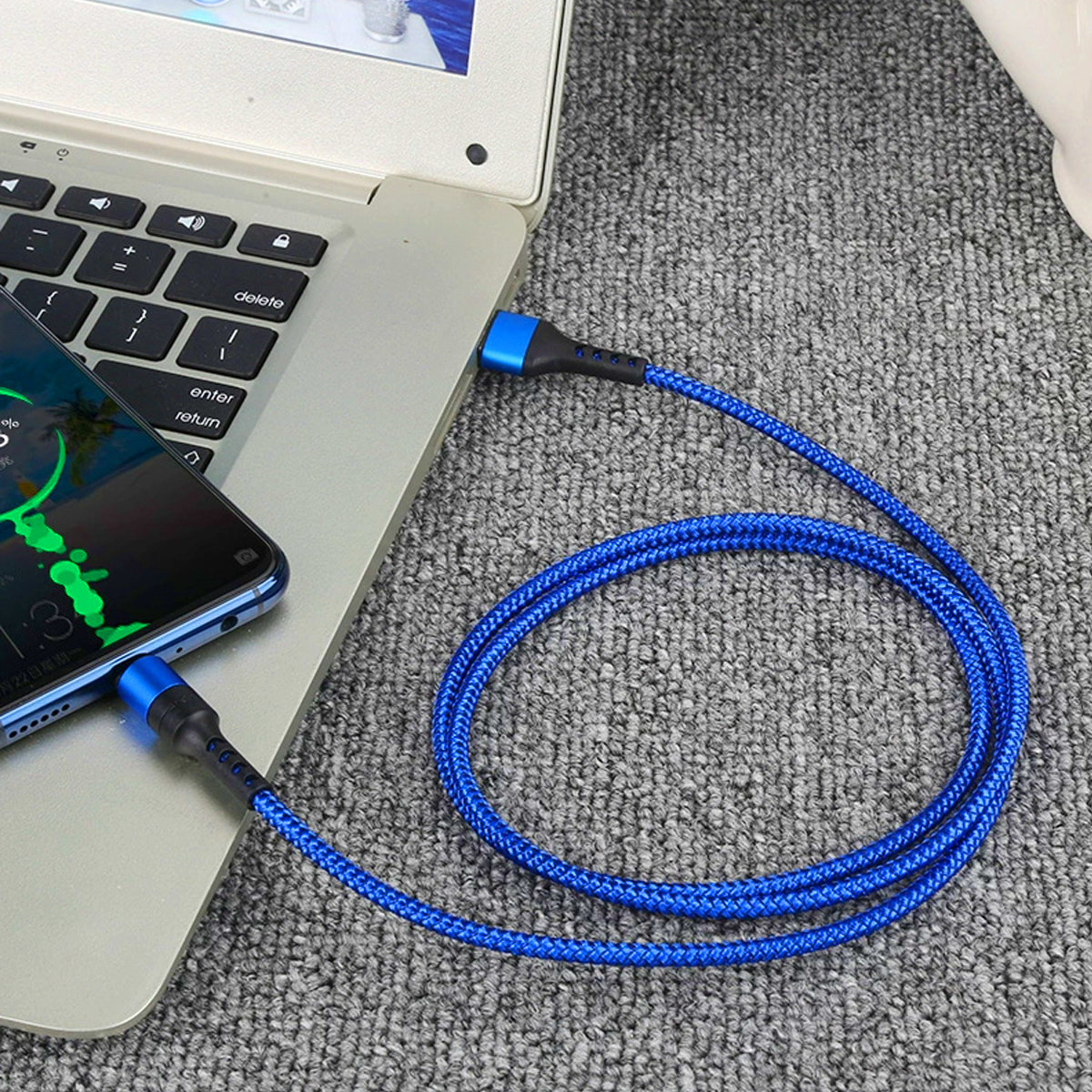 Ein blaues Ladekabel ist mit einem Telefon und einem Laptop verbunden. Der Laptop ist geöffnet.