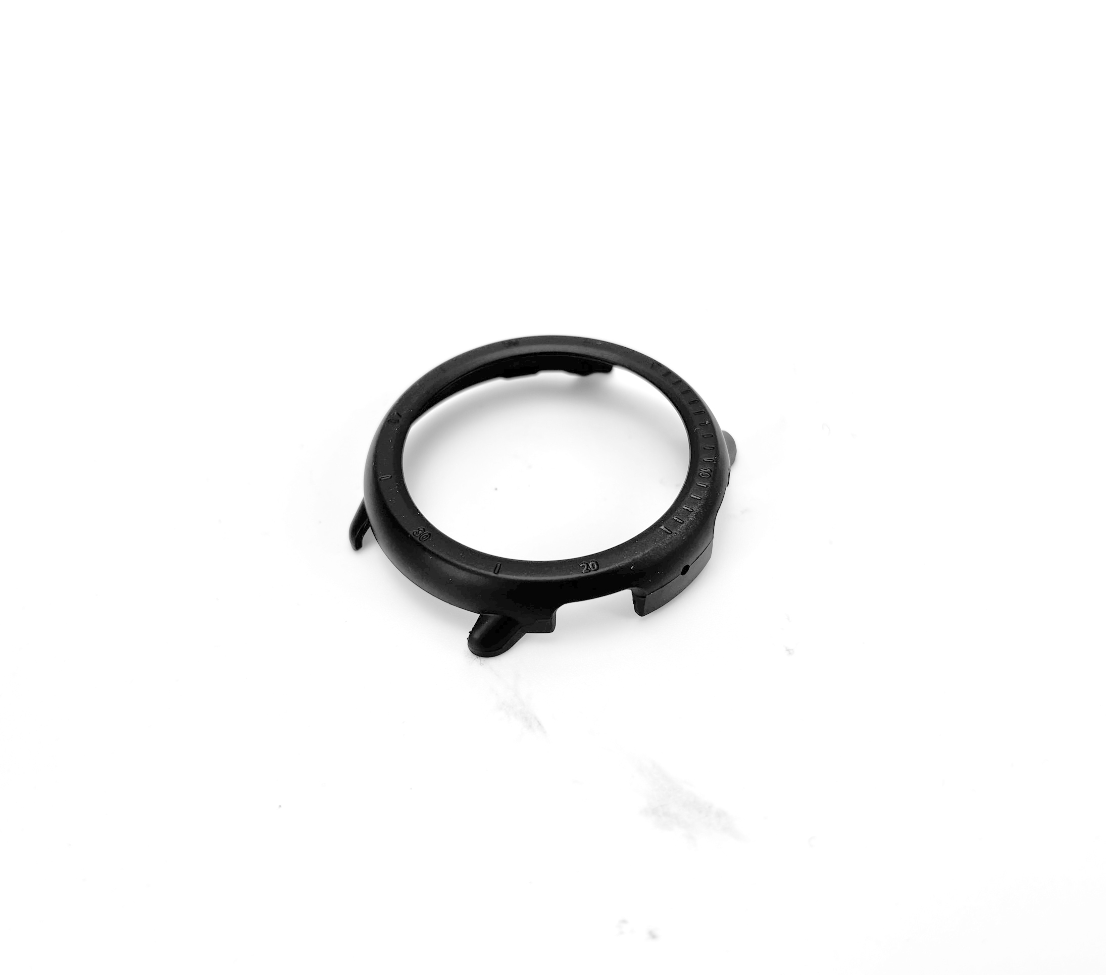 Componente della cassa dell'orologio nera, circolare con ritagli, su una superficie bianca.