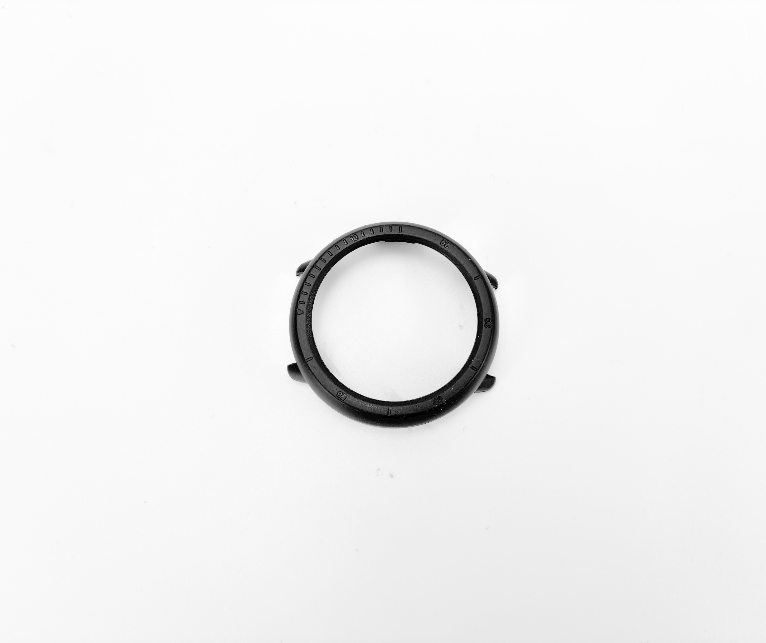Ghiera dell'orologio nera, forma rotonda con numeri e indicatori incisi, sfondo bianco.