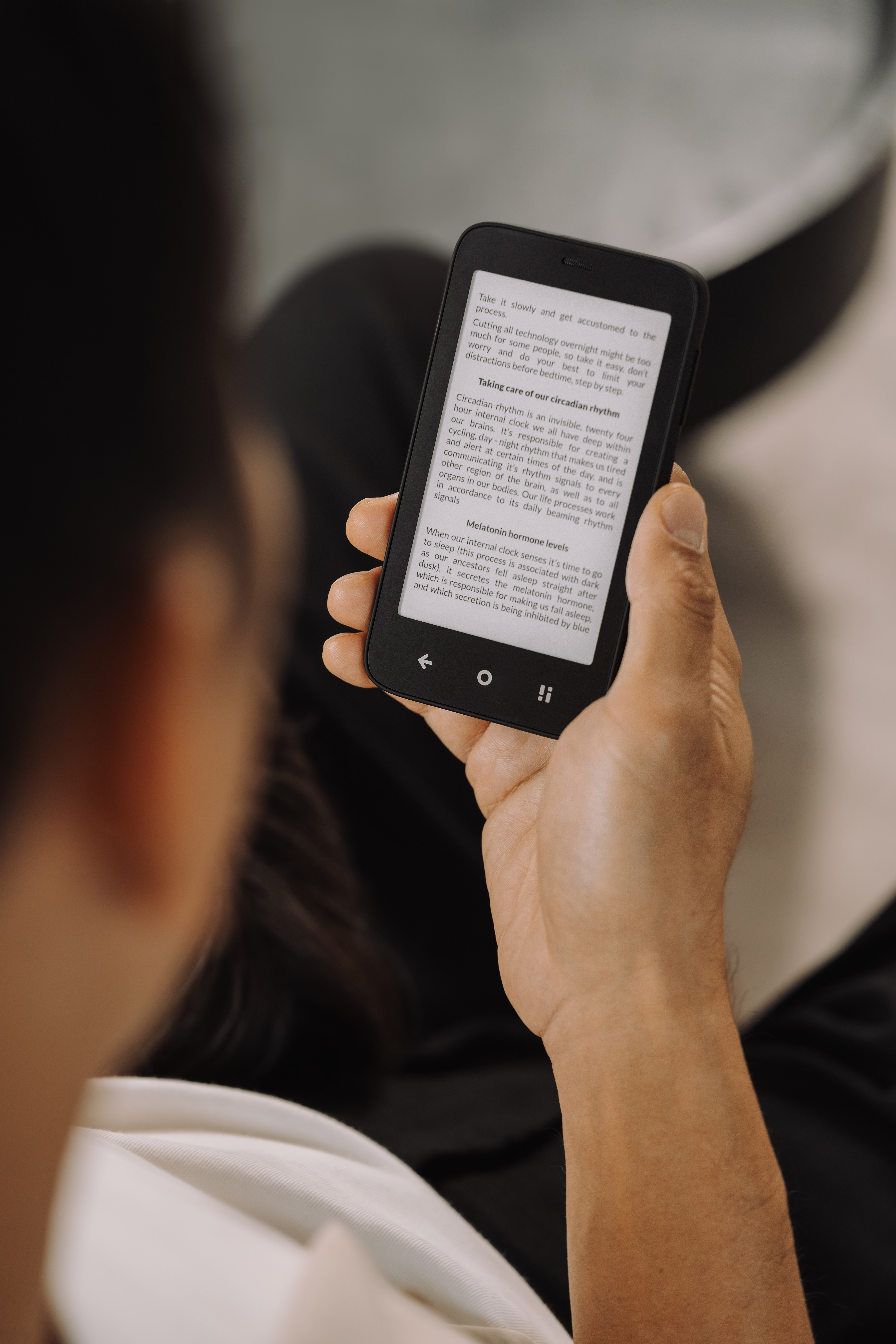 Die Hand einer Person, die einen schwarzen E-Reader hält. Der Bildschirm zeigt Text aus einem Buch über zirkadiane Rhythmen.
