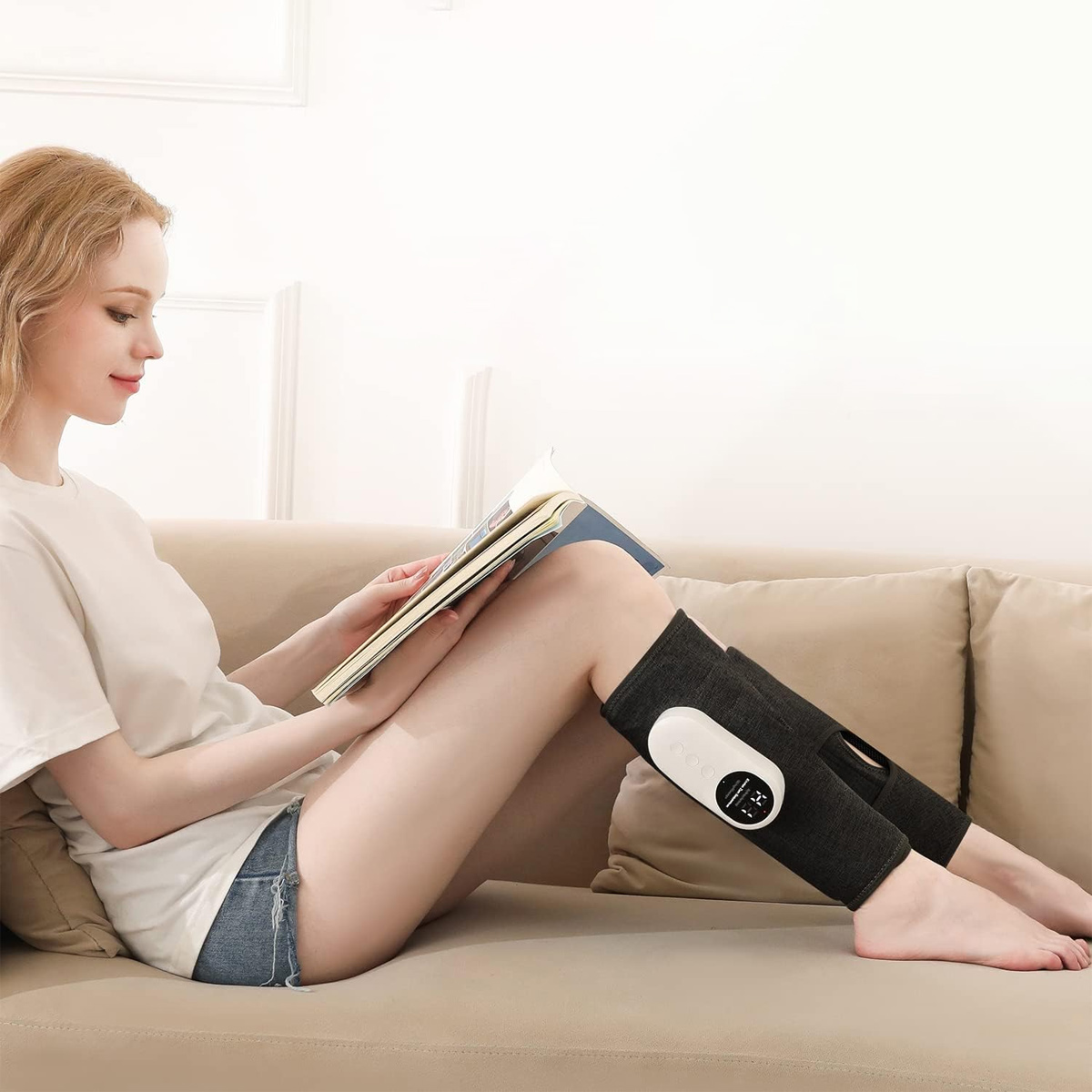Eine Frau sitzt auf einem Sofa und liest ein Buch, mit schwarzen Beinwickeln. Die Bandagen haben weiße Bedienfelder.