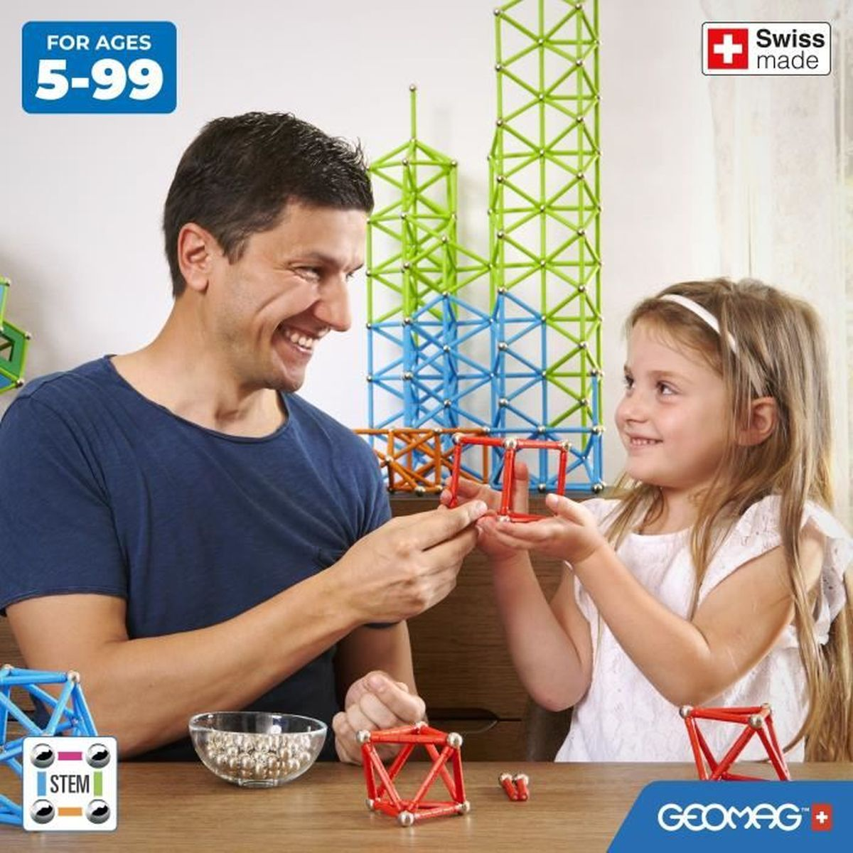 Ein Mann und ein Mädchen bauen geometrische Formen mit Geomag-Konstruktionsstäben und Metallkugeln.