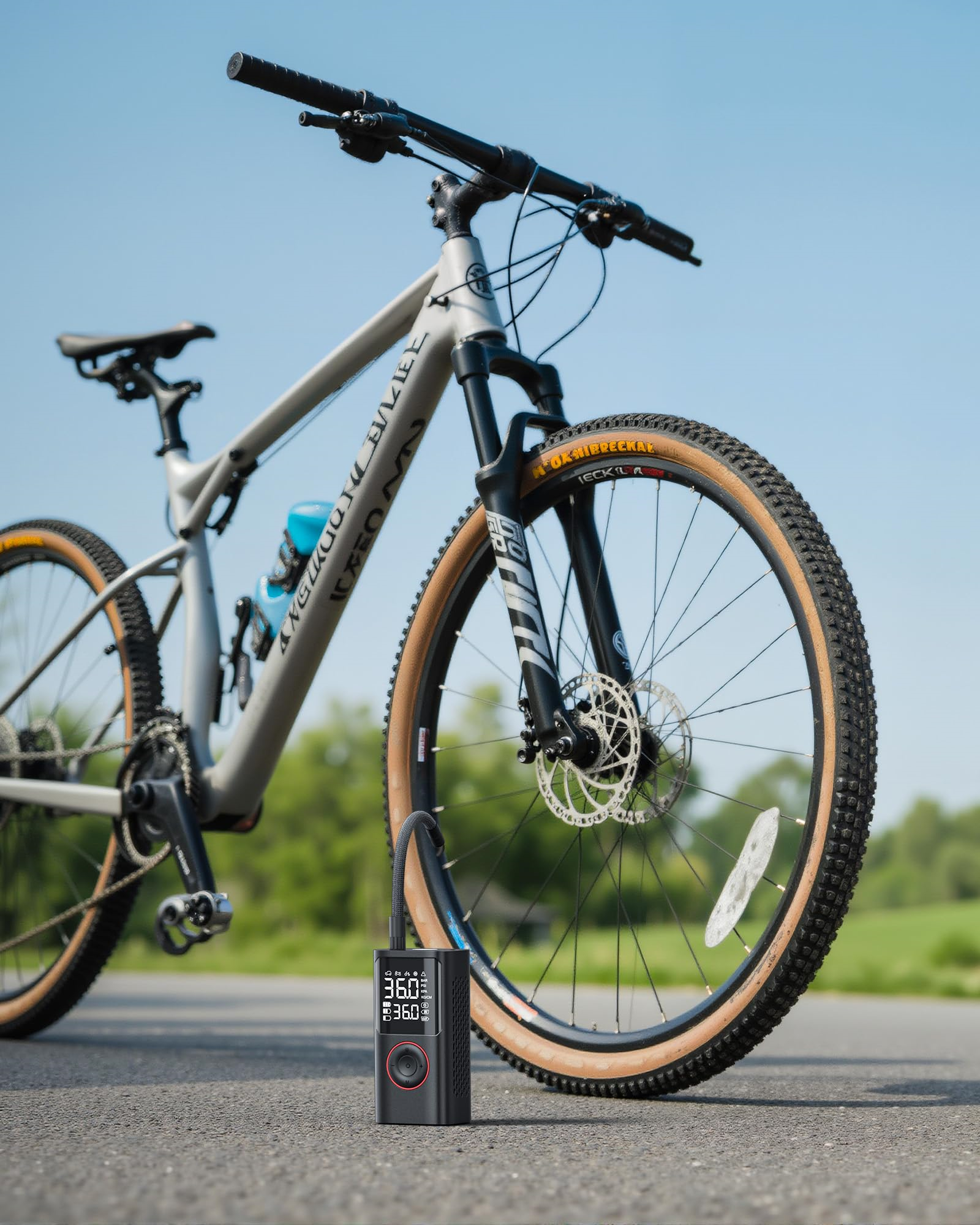 Ein schwarzes Fahrrad mit einer Pumpe am Reifen. Der Hintergrund ist blauer Himmel und grünes Feld.