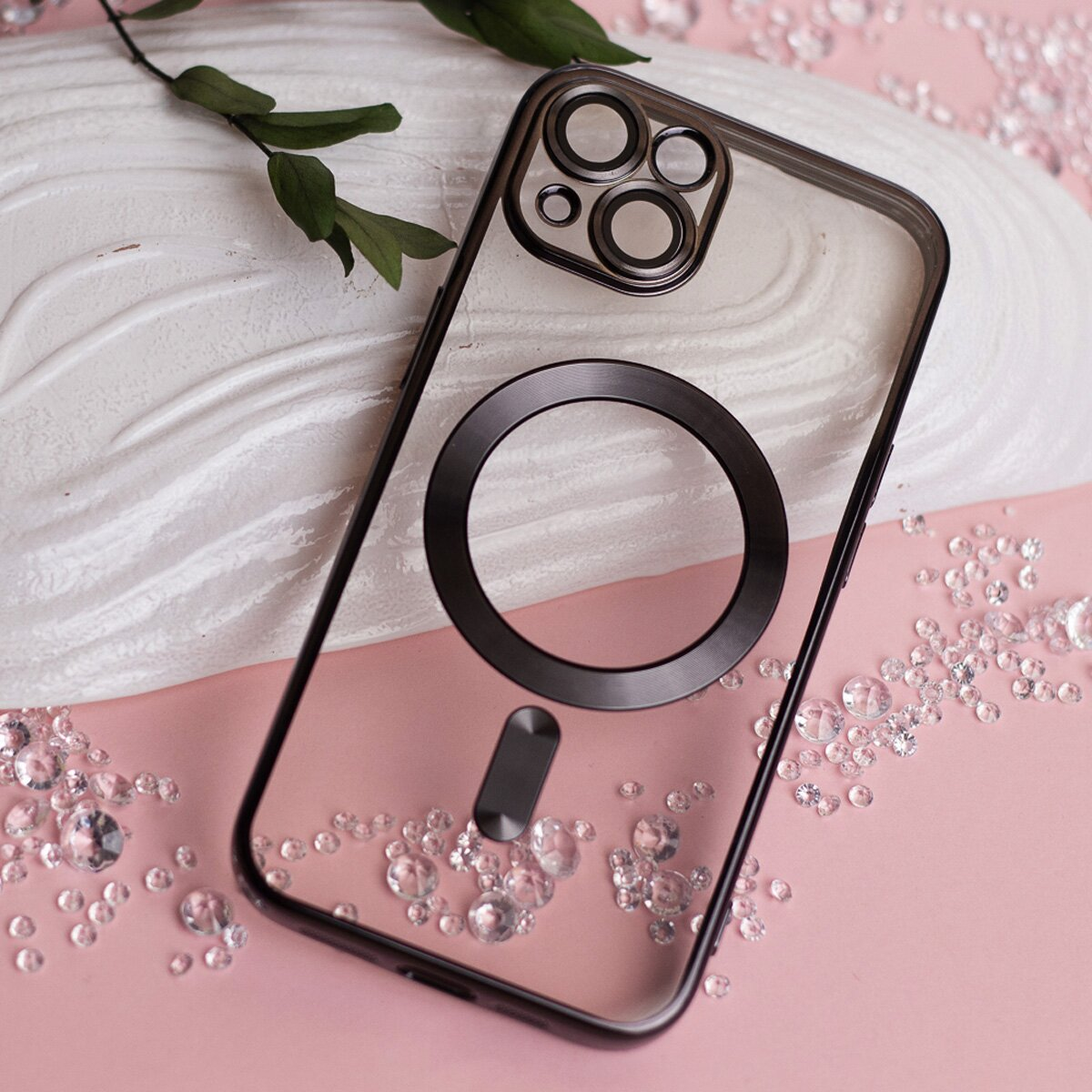 Transparente Handyhülle mit schwarzem Rahmen und MagSafe-Kreis. Dekoriert mit Kristallen, pinker Hintergrund.