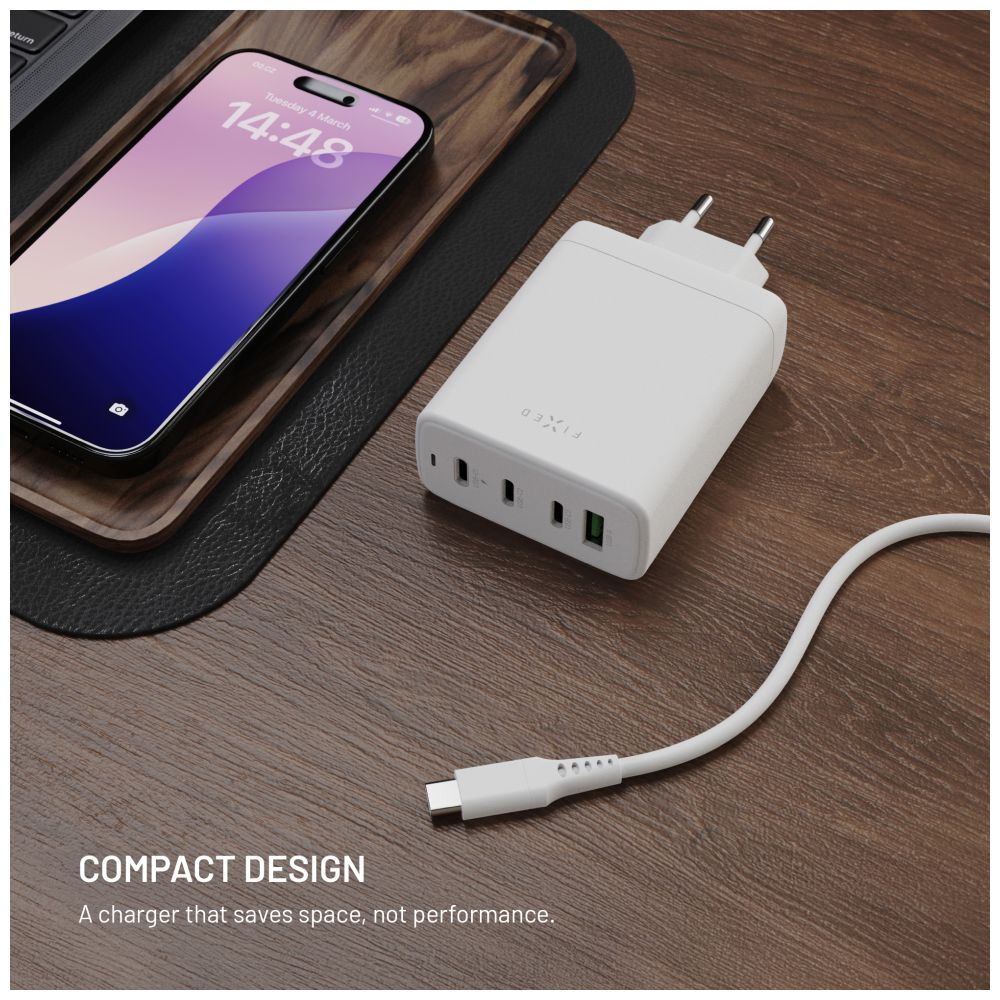 Weißes Ladegerät mit USB-Anschlüssen und weißem Kabel. Daneben liegt ein Telefon.