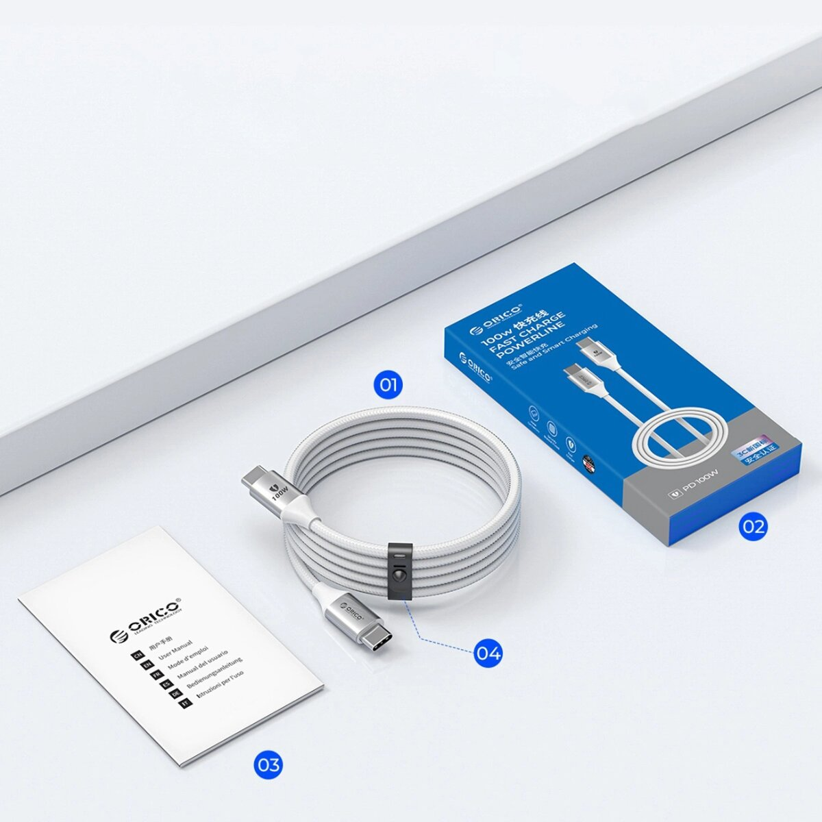 Ein weißes Ladekabel, eine Bedienungsanleitung und eine blau-weiße Box mit Text auf weißem Hintergrund.
