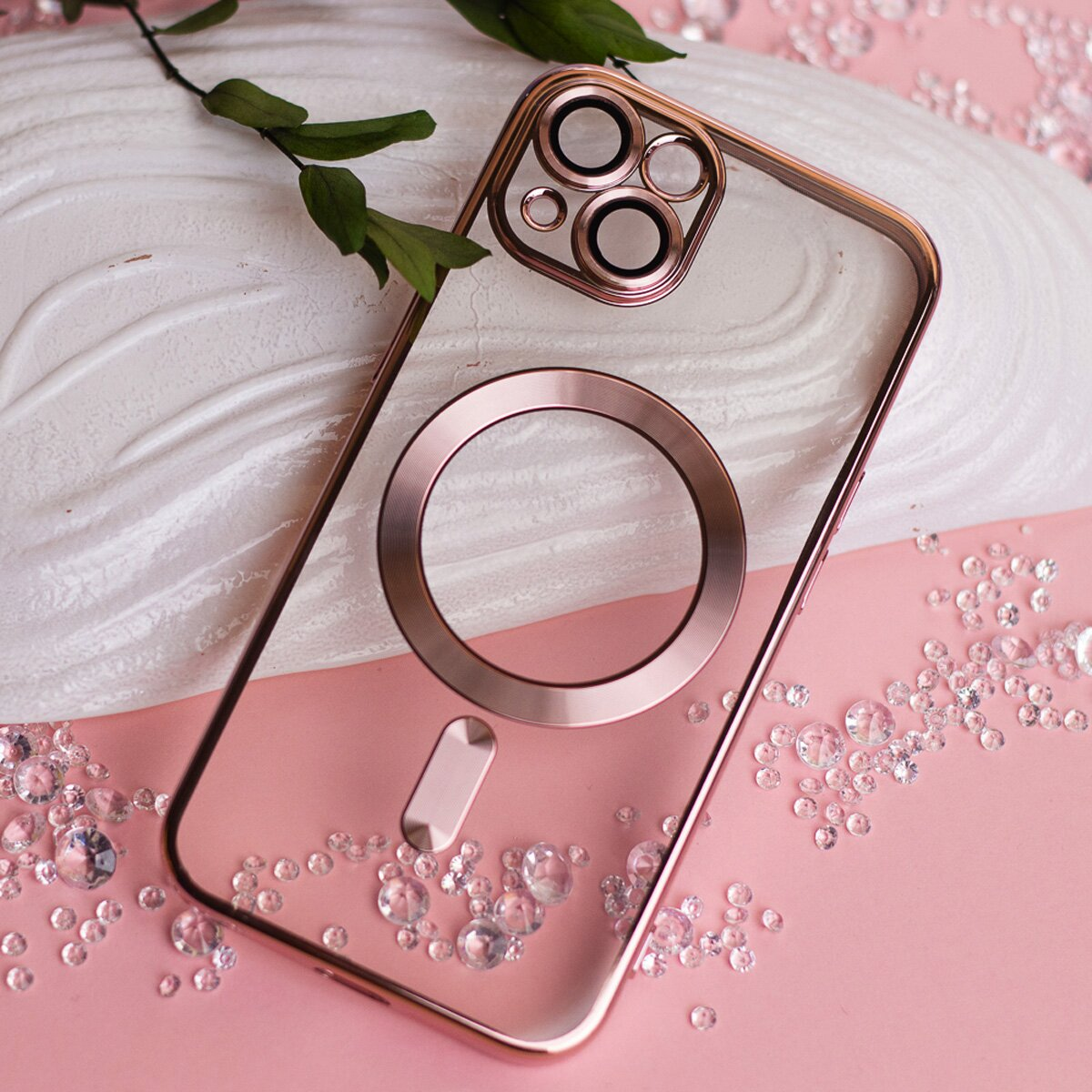 Transparente Handyhülle mit roségoldfarbenen Akzenten, Kristallen und einem Blatt auf rosa Grund.