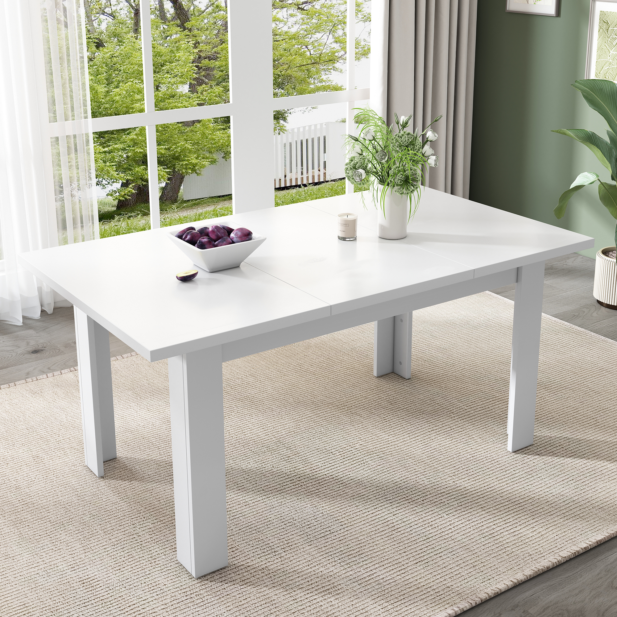 Ein weißer Holztisch für das Essen, mit einer Schüssel Pflaumen und einer Blumenvase.