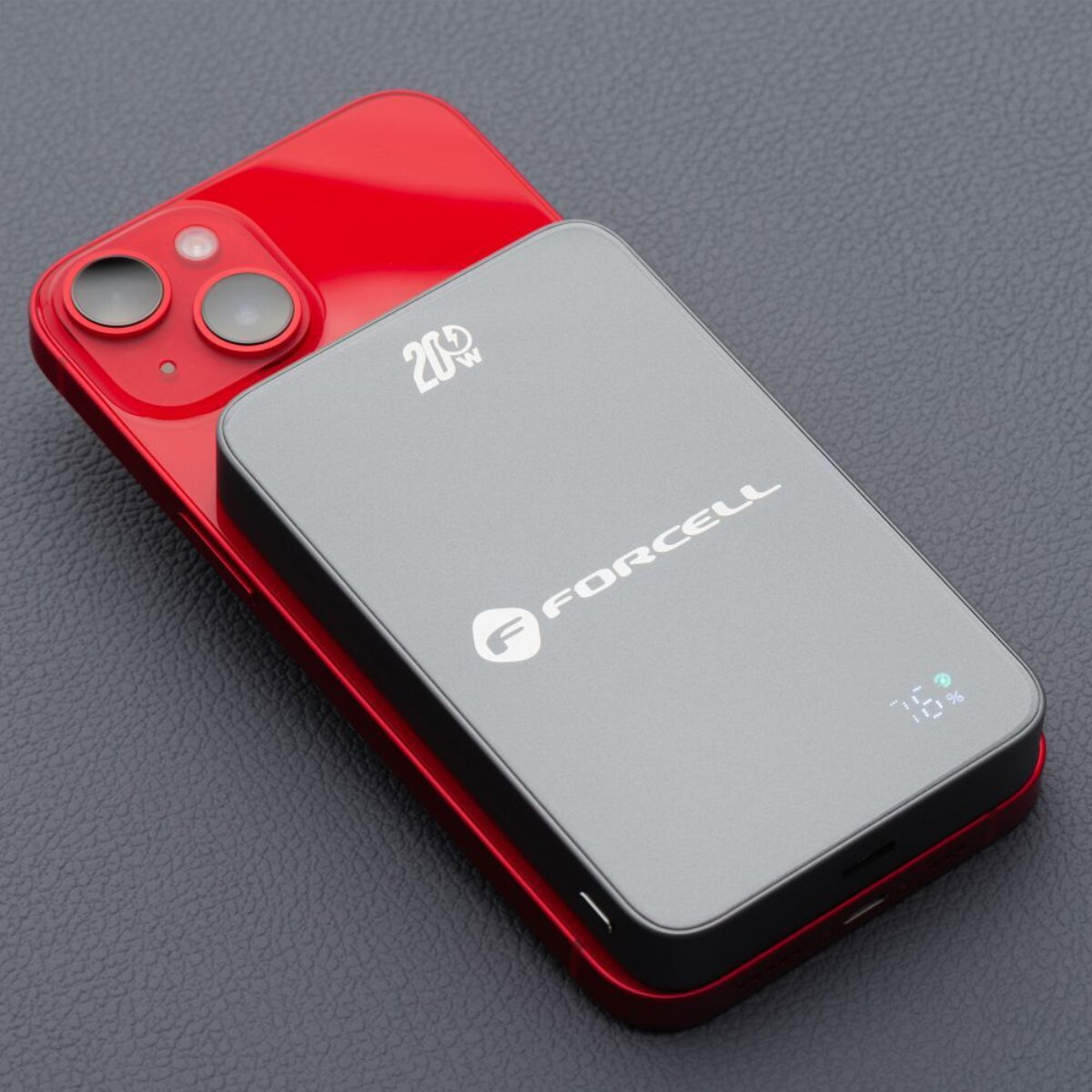 Powerbank auf einem roten Telefon. Die Powerbank ist grau mit der Marke FORCELL. Das Telefon befindet sich auf dunkler Oberfläche.