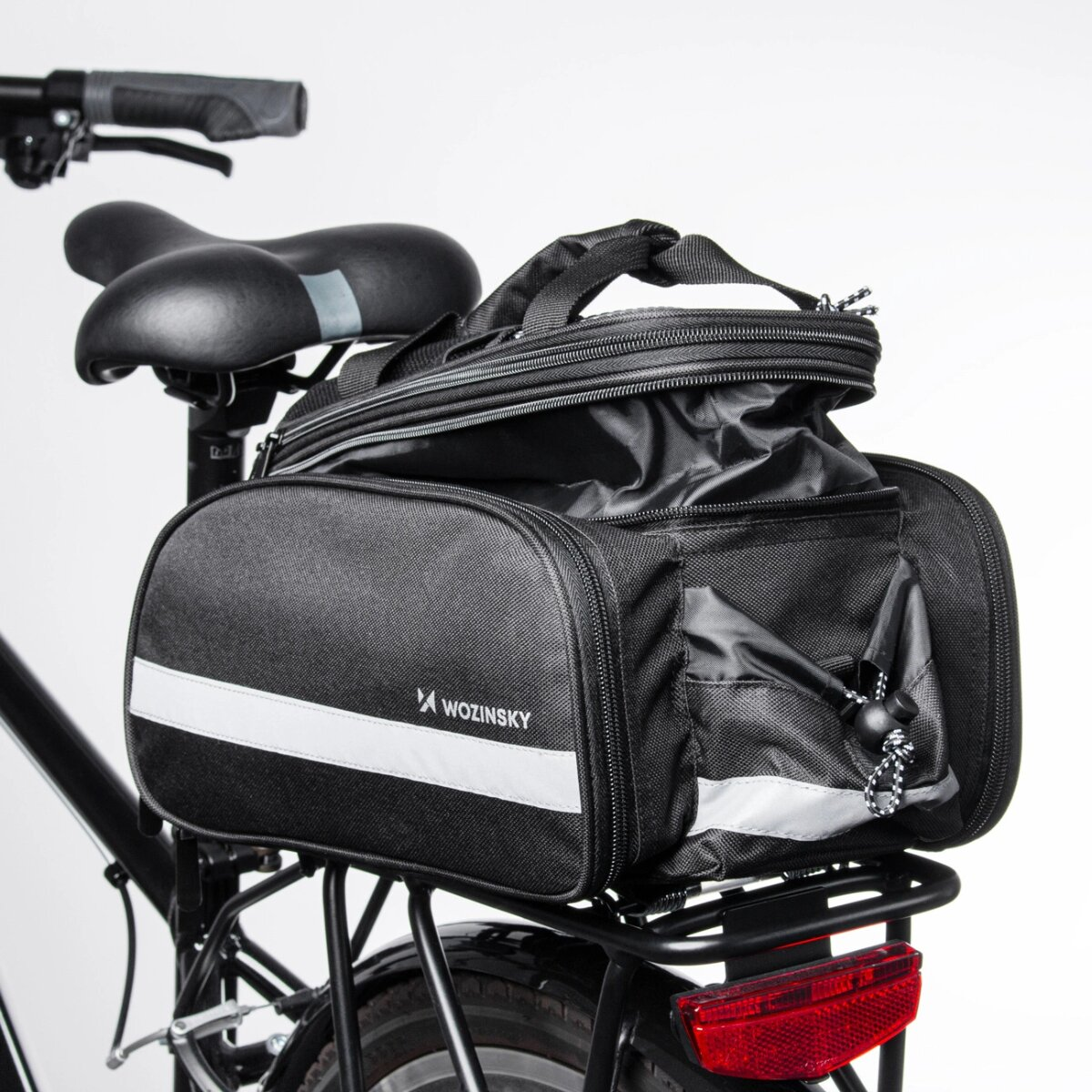 Eine schwarze Fahrradtasche mit Reflexstreifen an einem Fahrrad, vor weißem Hintergrund.