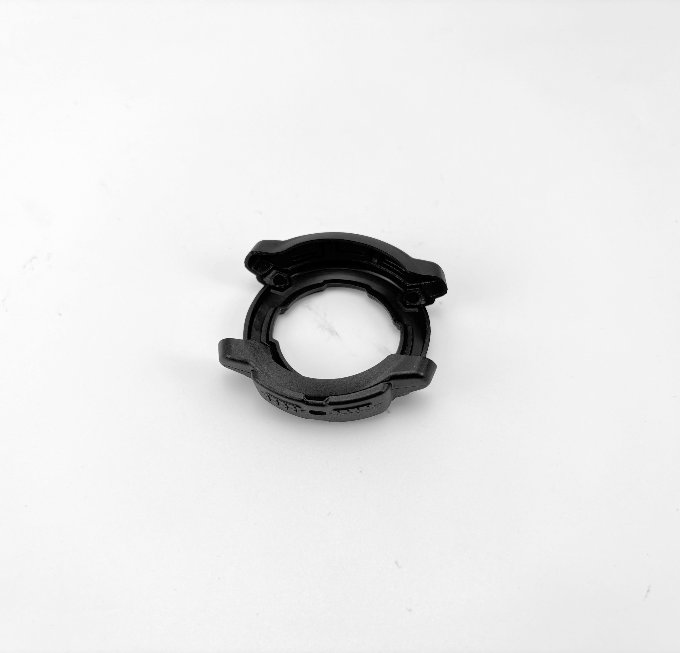 Pezzo di auto in plastica nera con design circolare, aperto su un lato, isolato su sfondo bianco.