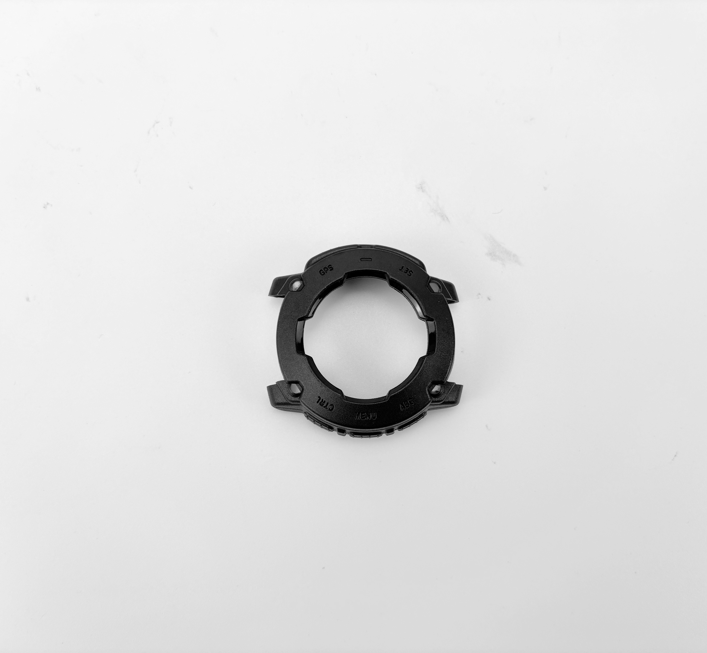 Pezzo di auto in plastica nera con design circolare, con testo, su sfondo bianco.
