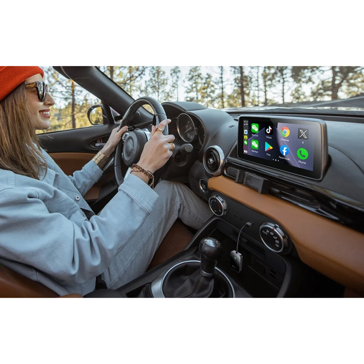 Frau fährt Auto und benutzt einen Touchscreen mit verschiedenen App-Symbolen.