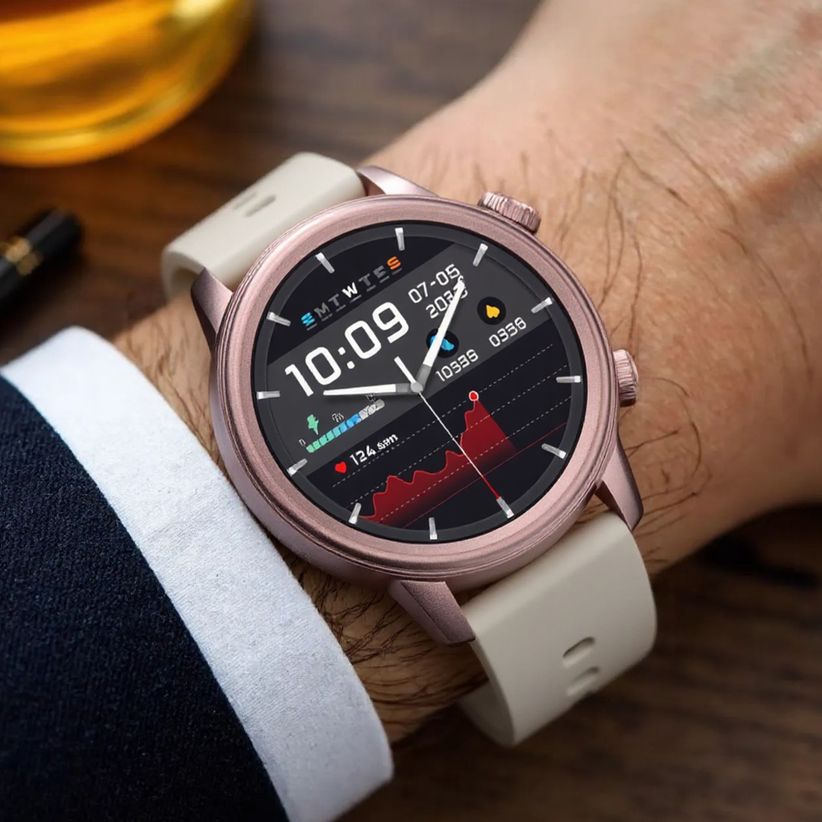 Eine roségoldene Smartwatch am Handgelenk. Das Display zeigt die Zeit, das Datum und die Herzfrequenzdaten.