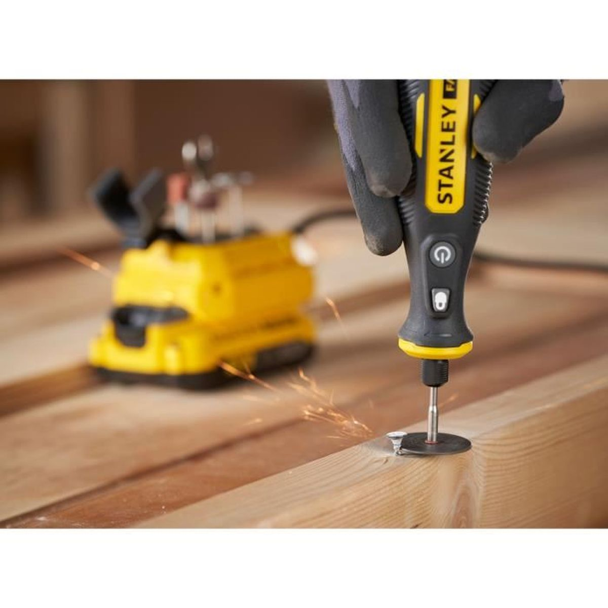 Ein Rotationswerkzeug schneidet Holz, Funken fliegen, gehalten von einer behandschuhten Hand. Gelbes Werkzeug.
