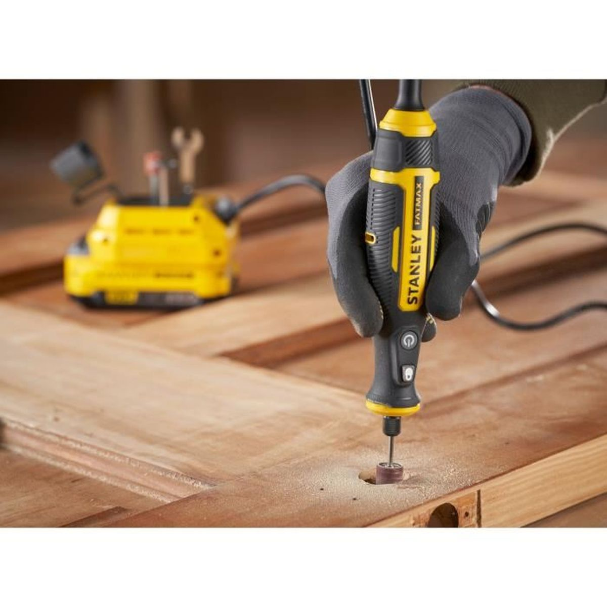 Eine behandschuhte Hand benutzt ein Rotationswerkzeug, um ein Loch in eine Holztür zu bohren.