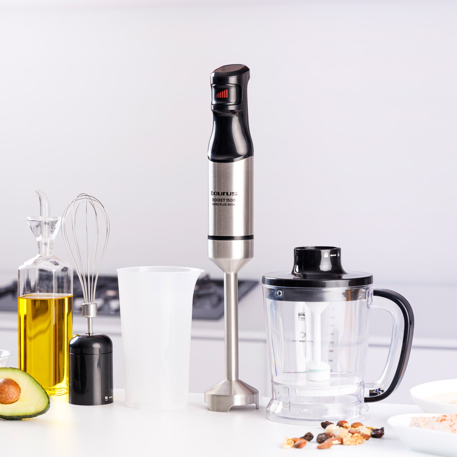 Handmixer mit Zutaten und Zubehör auf weißer Oberfläche.