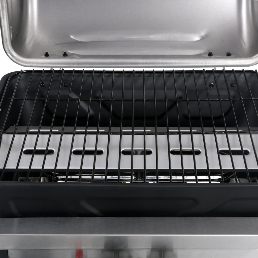 Primo piano dell'interno di una griglia. Ha una griglia nera, un coperchio del bruciatore argentato e una parte superiore in acciaio inossidabile.