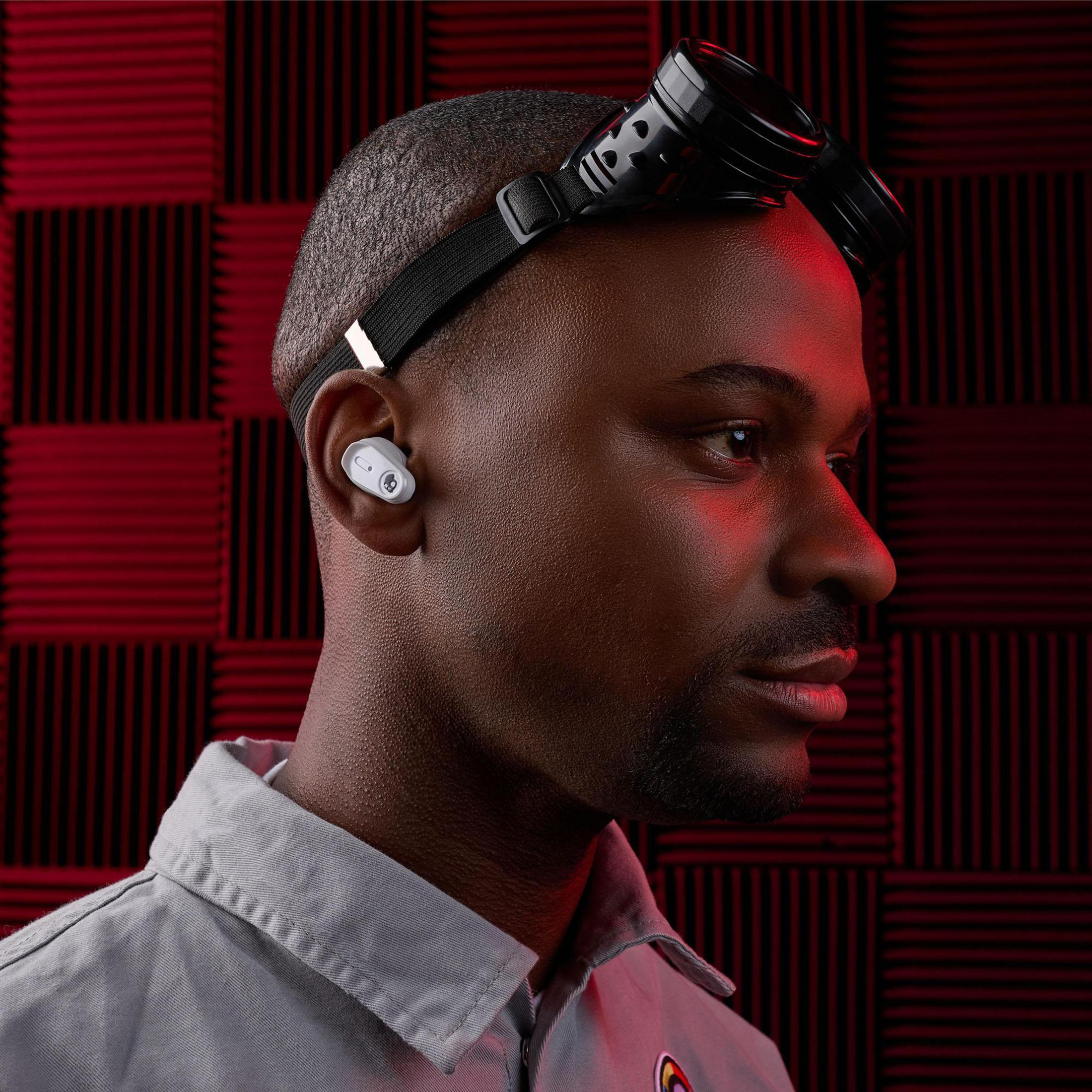 Mężczyzna ze słuchawką, goglami, czerwoną ścianą.