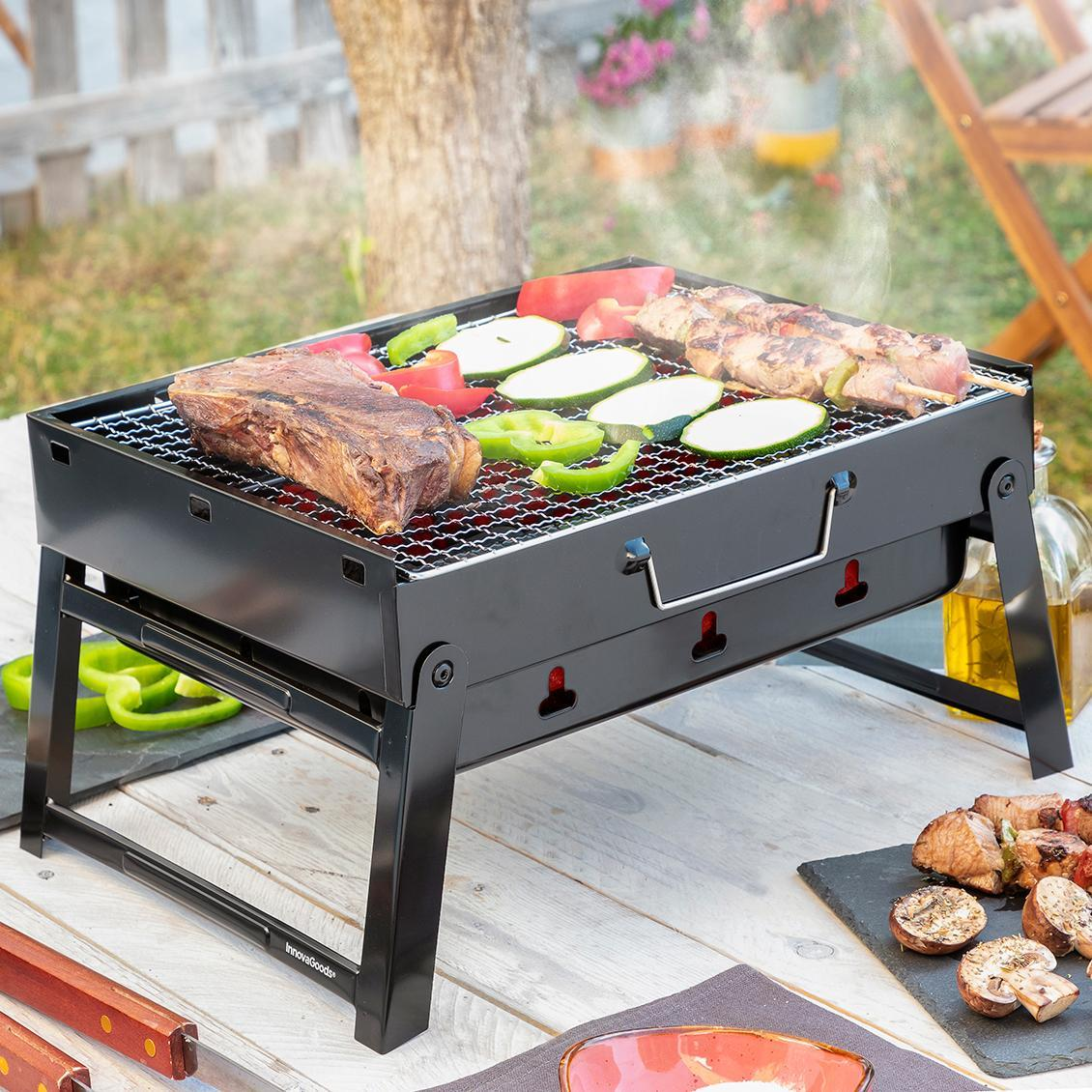 Ein schwarzer Grill mit gekochtem Essen auf einem Tisch, Gemüse und eine Flasche.