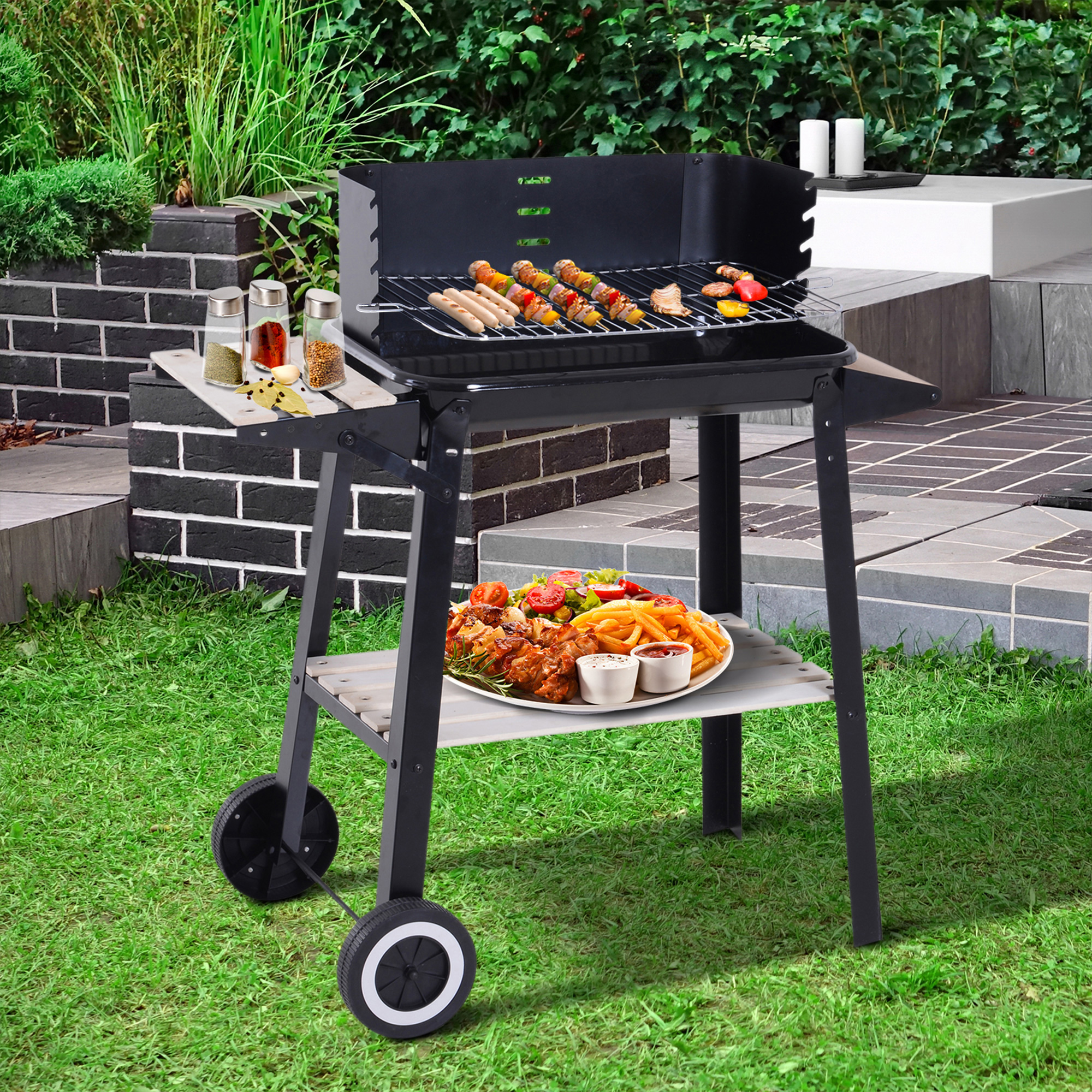 Un grill con cibo e condimenti si trova su un prato con un muro di mattoni, scale e vegetazione sullo sfondo.