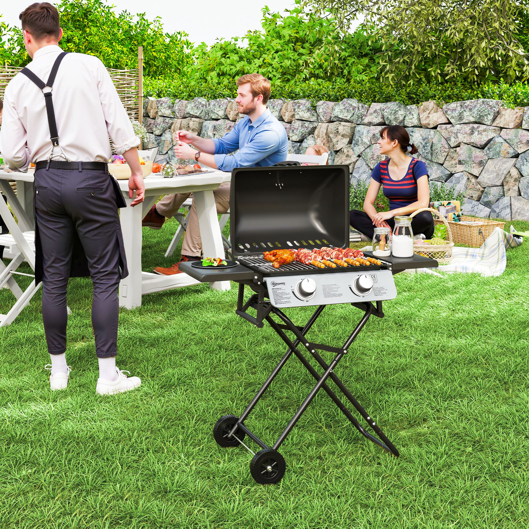 Persone che grigliano cibo su un barbecue su un prato verde. Un tavolo è allestito nelle vicinanze. Giorno soleggiato.