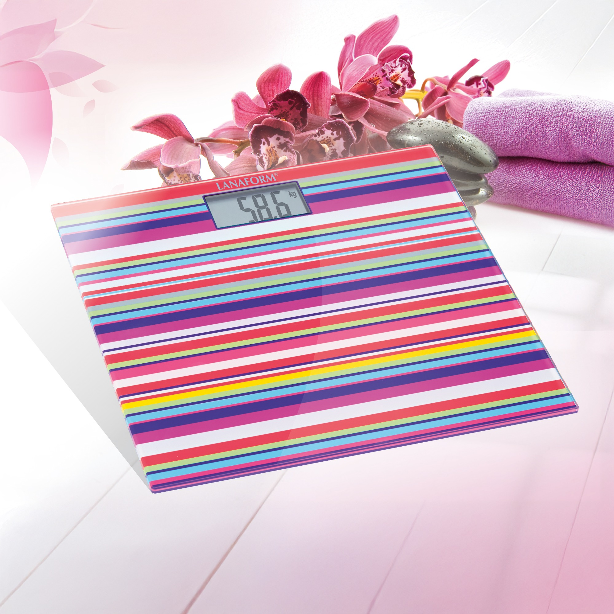 Pasiasta waga pokazuje 58,6 kg. Orchidee i ręczniki w tle.