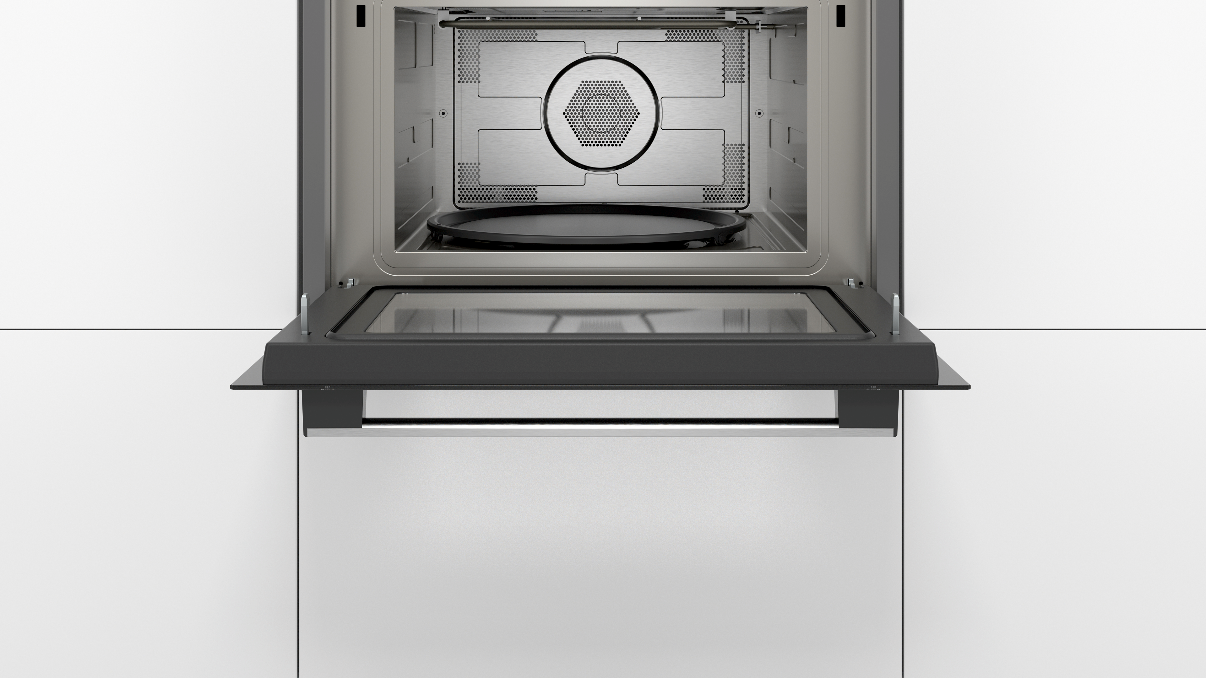 Microwave oven interior with open door. Stainless steel interior, a circular tray, and a glass door.