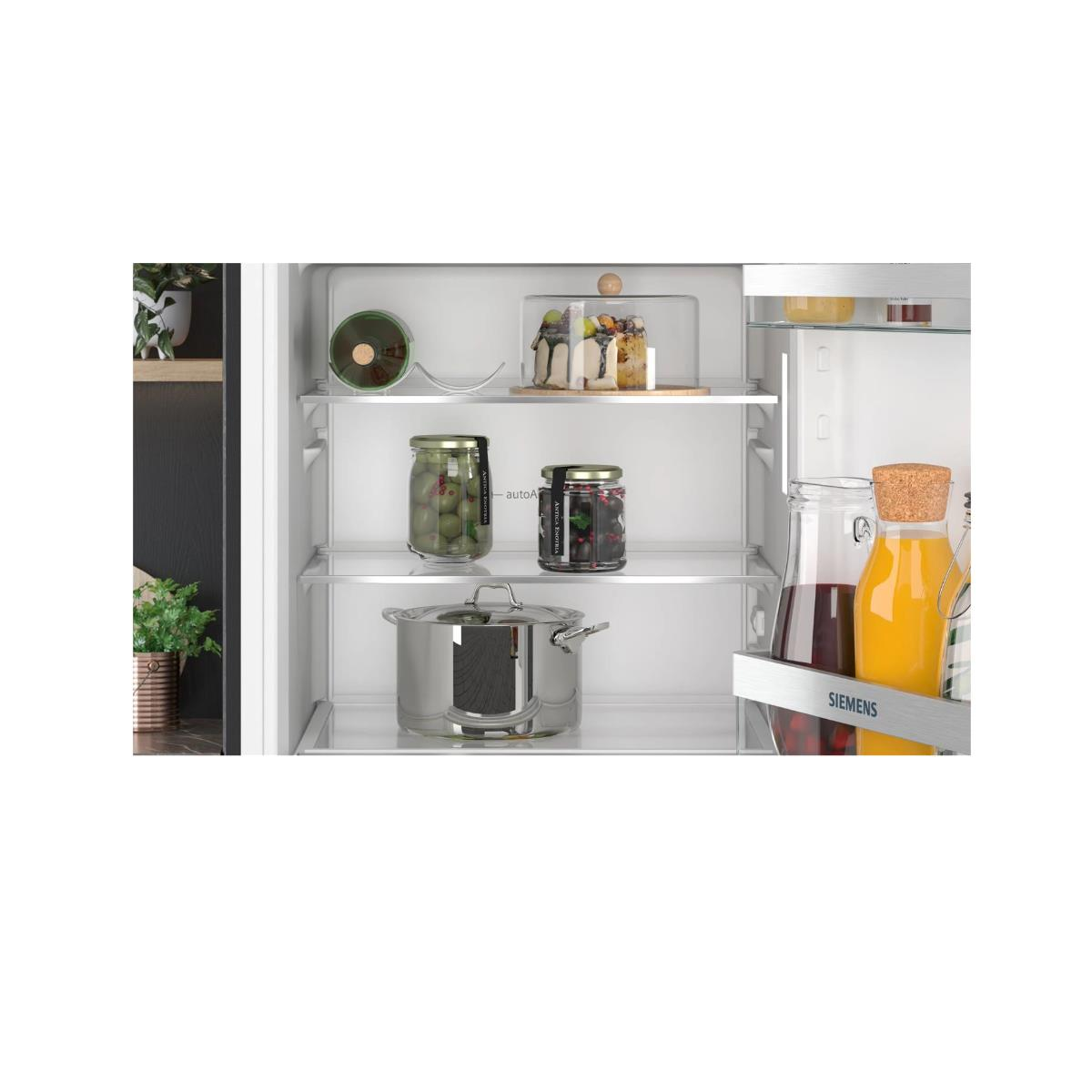 Interieur van een koelkast met diverse items op planken, waaronder potten, een pot en een lade.