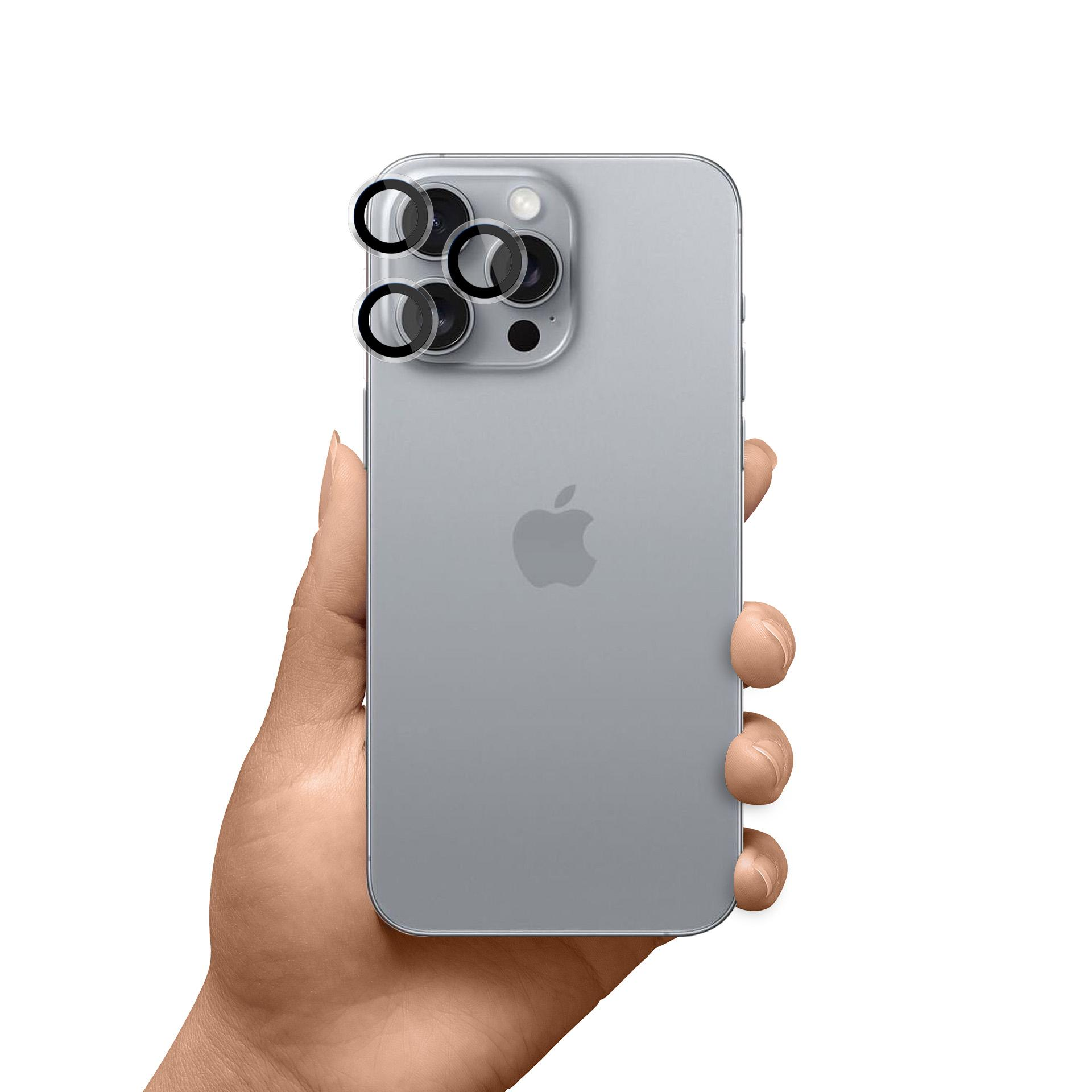 Mano che tiene un telefono argentato. Protezioni per lenti della fotocamera attaccate. Logo Apple sul telefono.