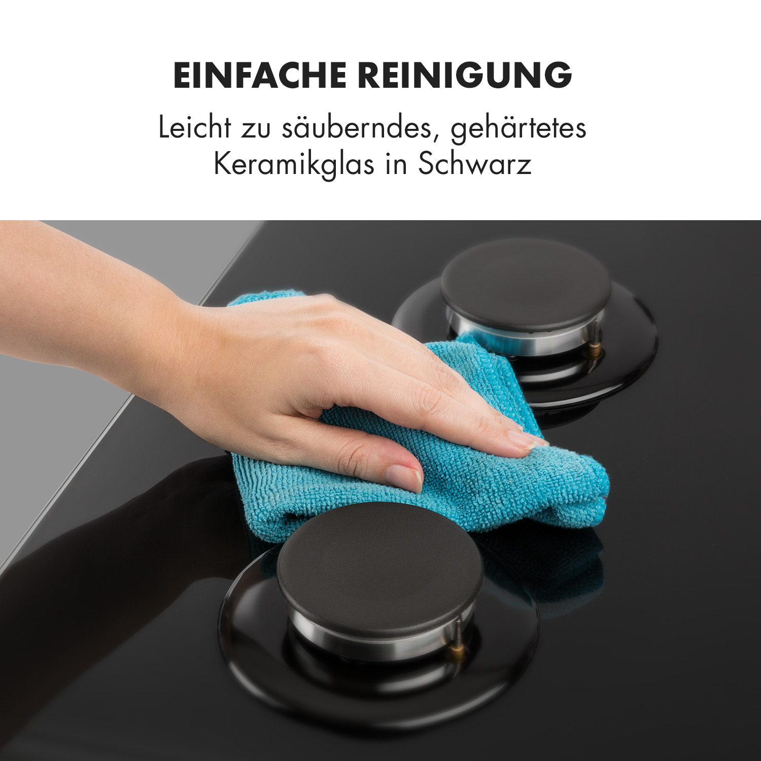 Una mujer limpia una placa de cocina negra con un paño azul. La placa tiene perillas y quemadores negros.