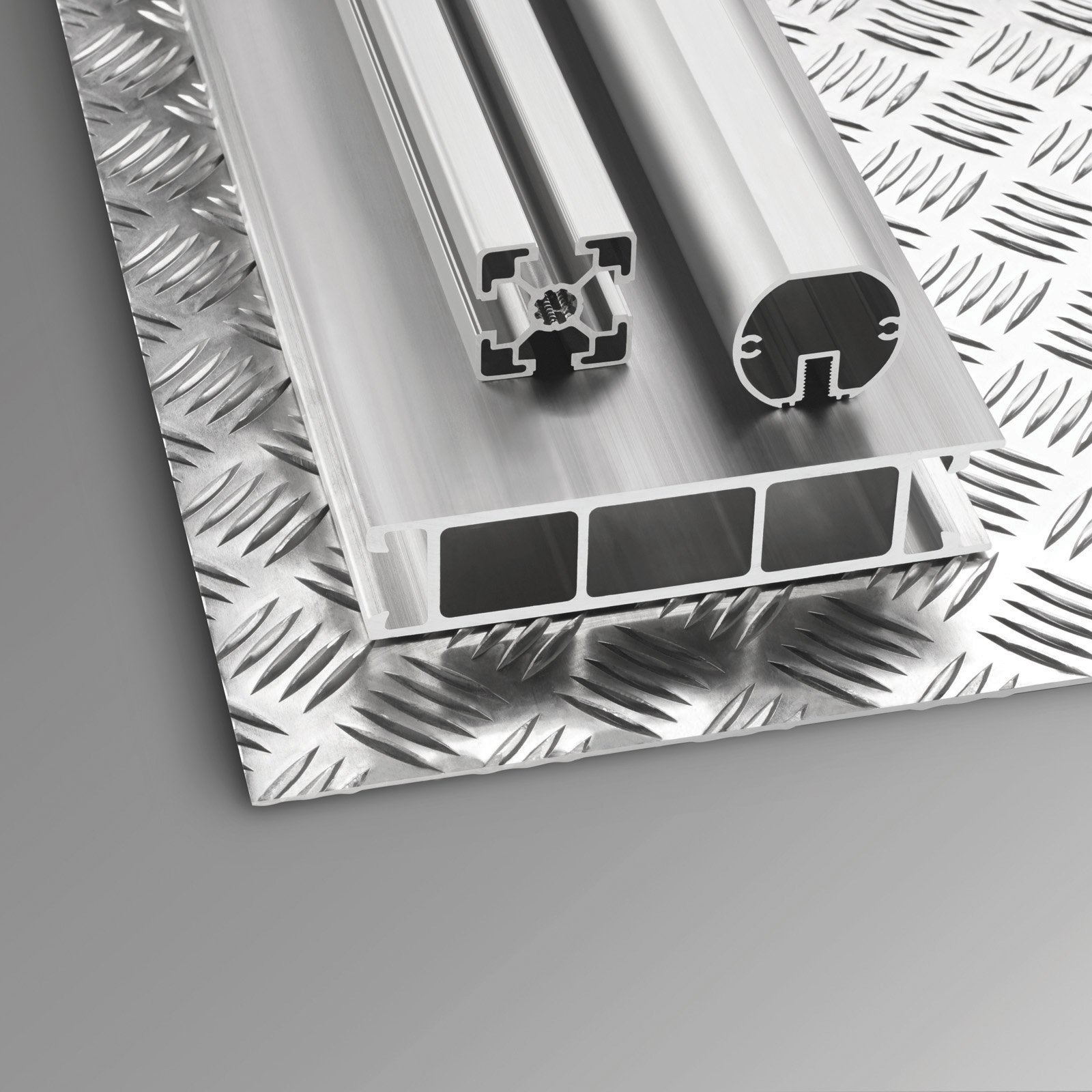 Metallische silberne Metallprofile auf einem Metallblech. Die Profile haben unterschiedliche Formen. Das Blech hat ein Diamantmuster.