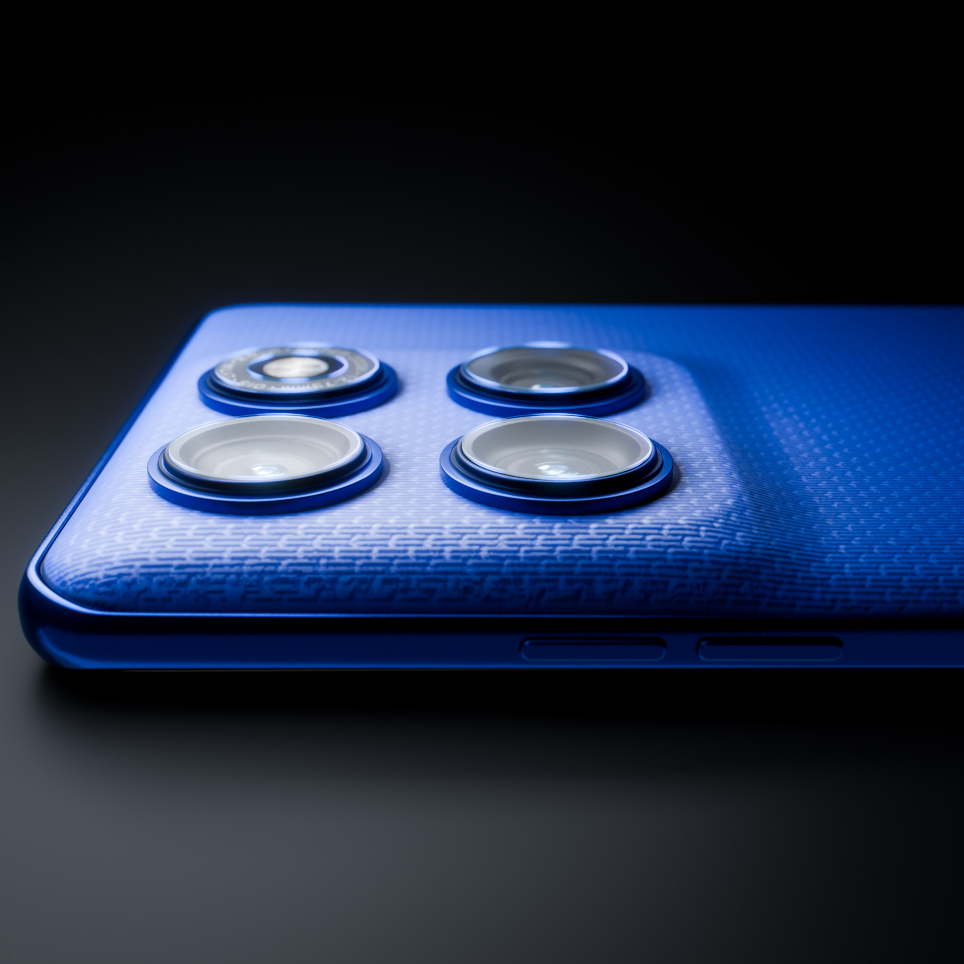 Primo piano del retro di uno smartphone blu. Ha quattro obiettivi e una superficie strutturata. Sfondo nero.