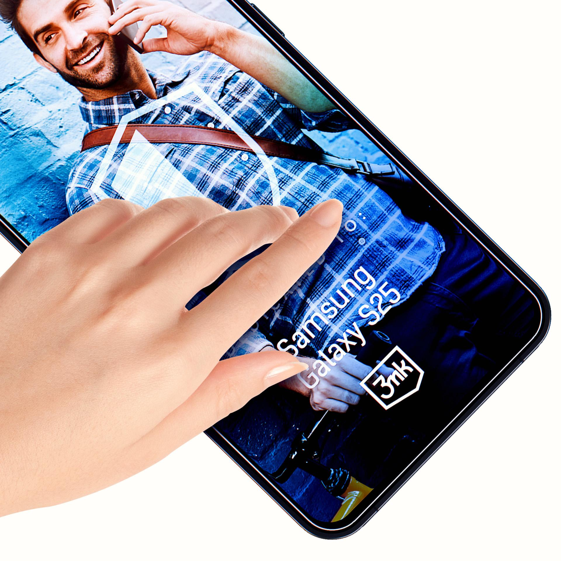 Dłoń dotyka telefonu, który wyświetla mężczyznę na ekranie. Telefon pokazuje Samsung Galaxy S25. Białe tło.