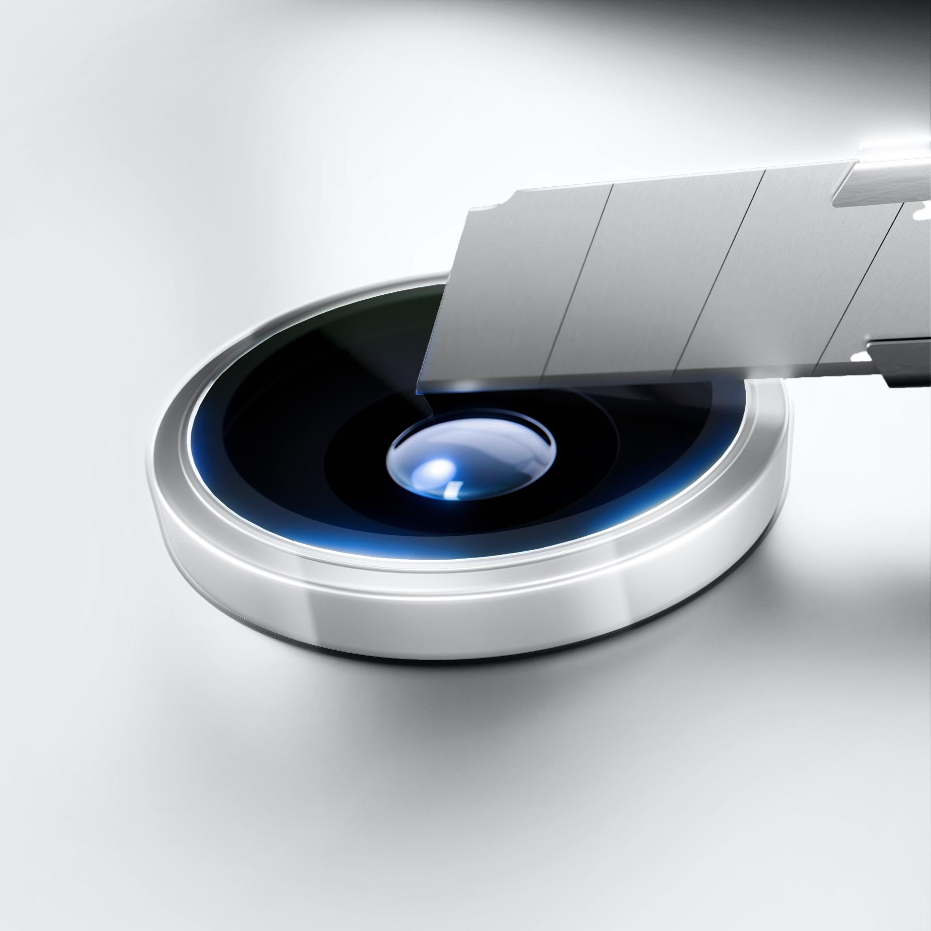 Ostrze noża do tapet nad okrągłym, metalicznym, czarno-niebieskim obiektem na białym tle. Obiekt jest na środku.