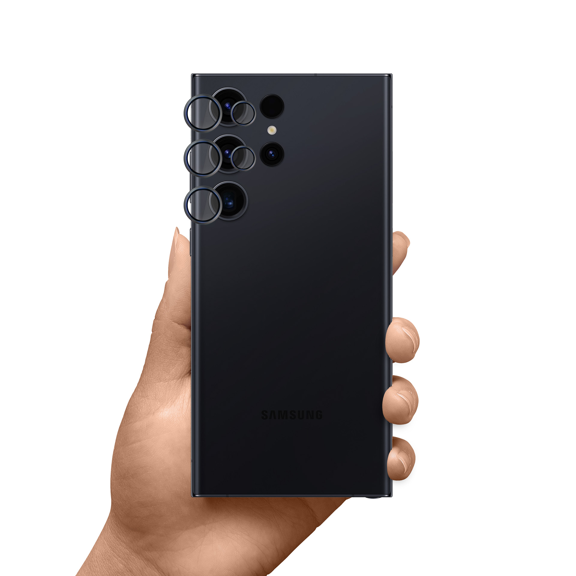 Ręka trzymająca czarny telefon Samsung. Telefon ma wiele obiektywów. Tło jest białe.