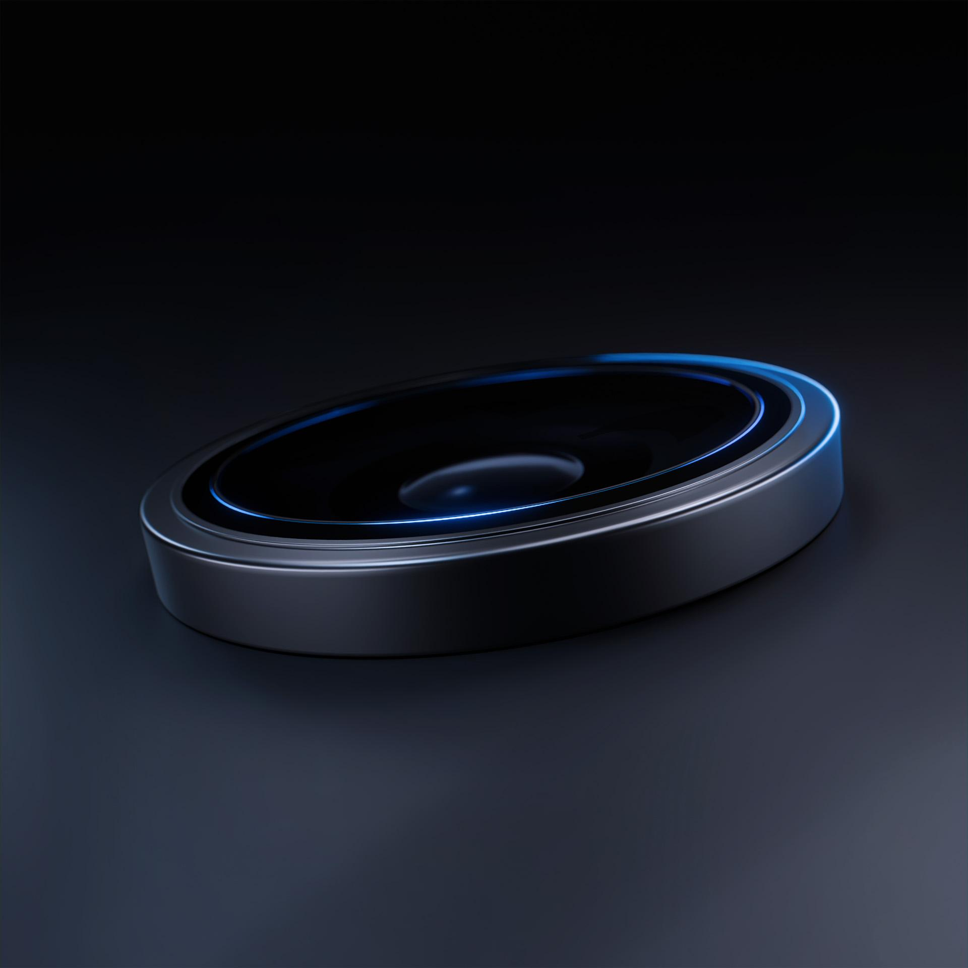 Metalowy, owalny obiekt z ciemnym środkiem i niebieskim świecącym pierścieniem na ciemnej powierzchni.