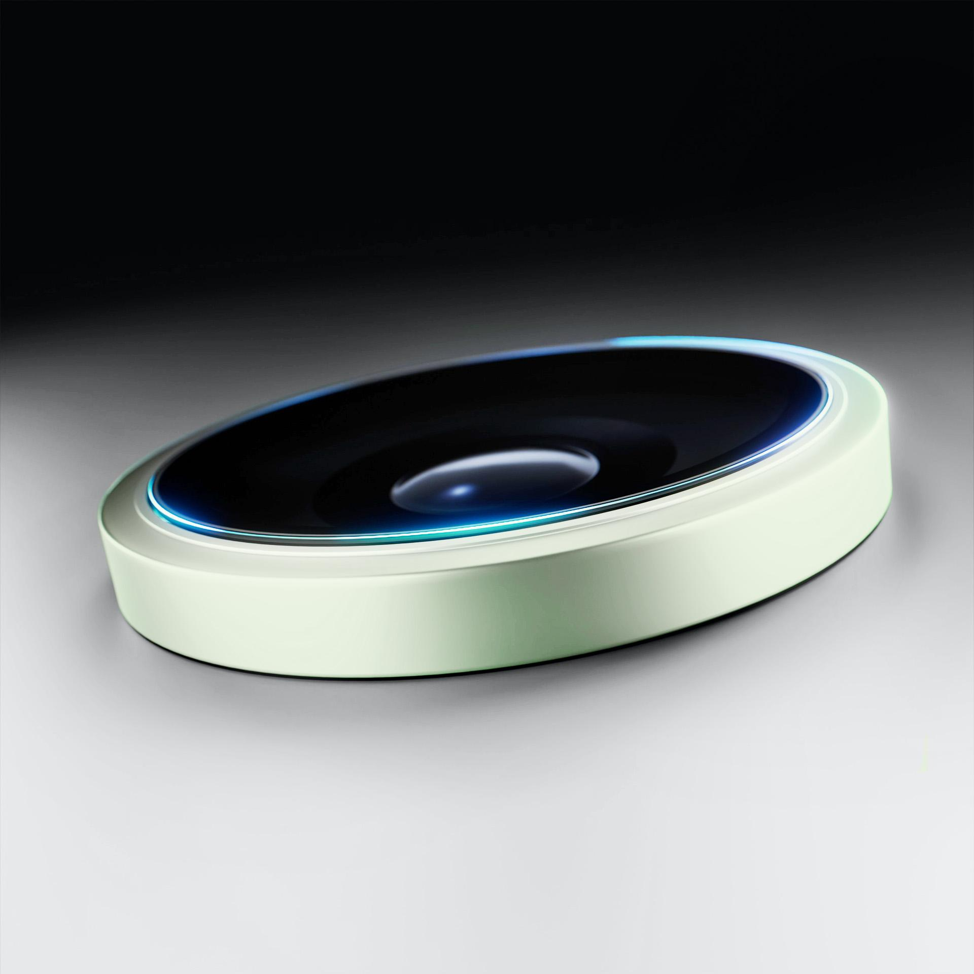 Primo piano di un dispositivo circolare con centro nero, circondato da un contorno verde chiaro e blu, su una superficie grigio chiaro.