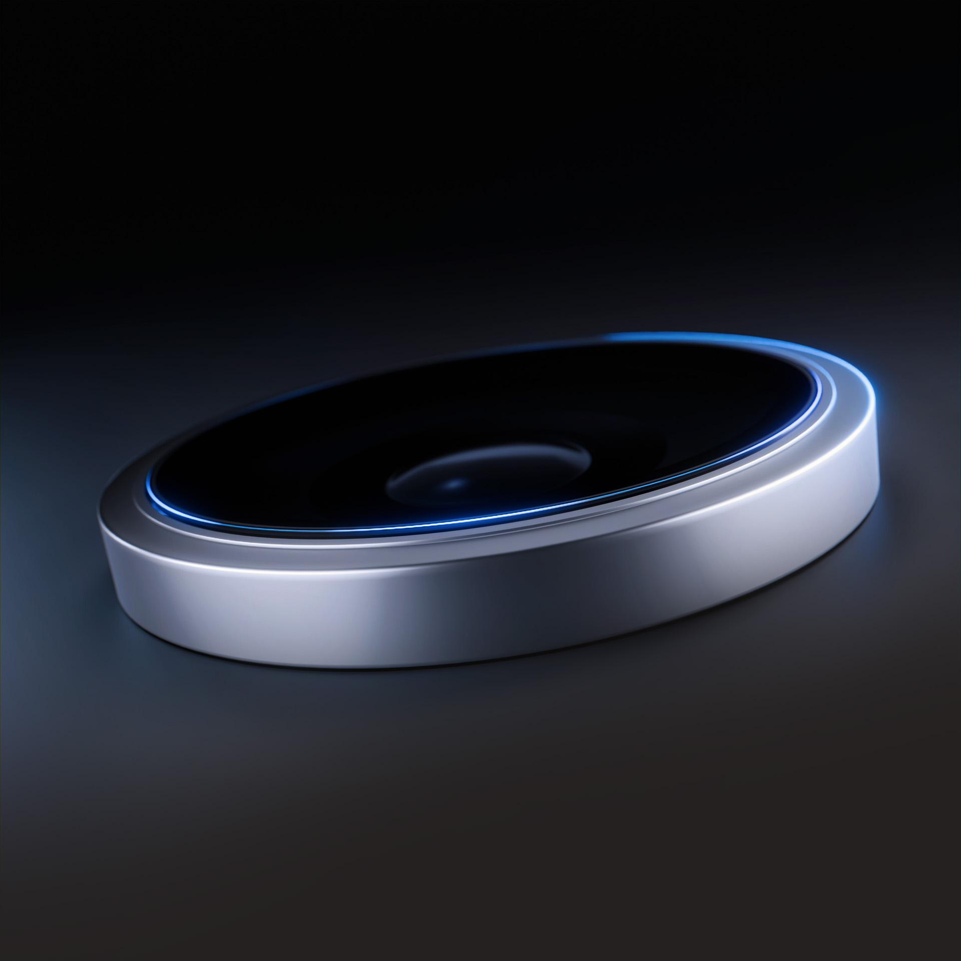 Futurystyczne, owalne urządzenie z czarnym wierzchem i srebrną podstawą, podświetlone niebieskim obrysem.