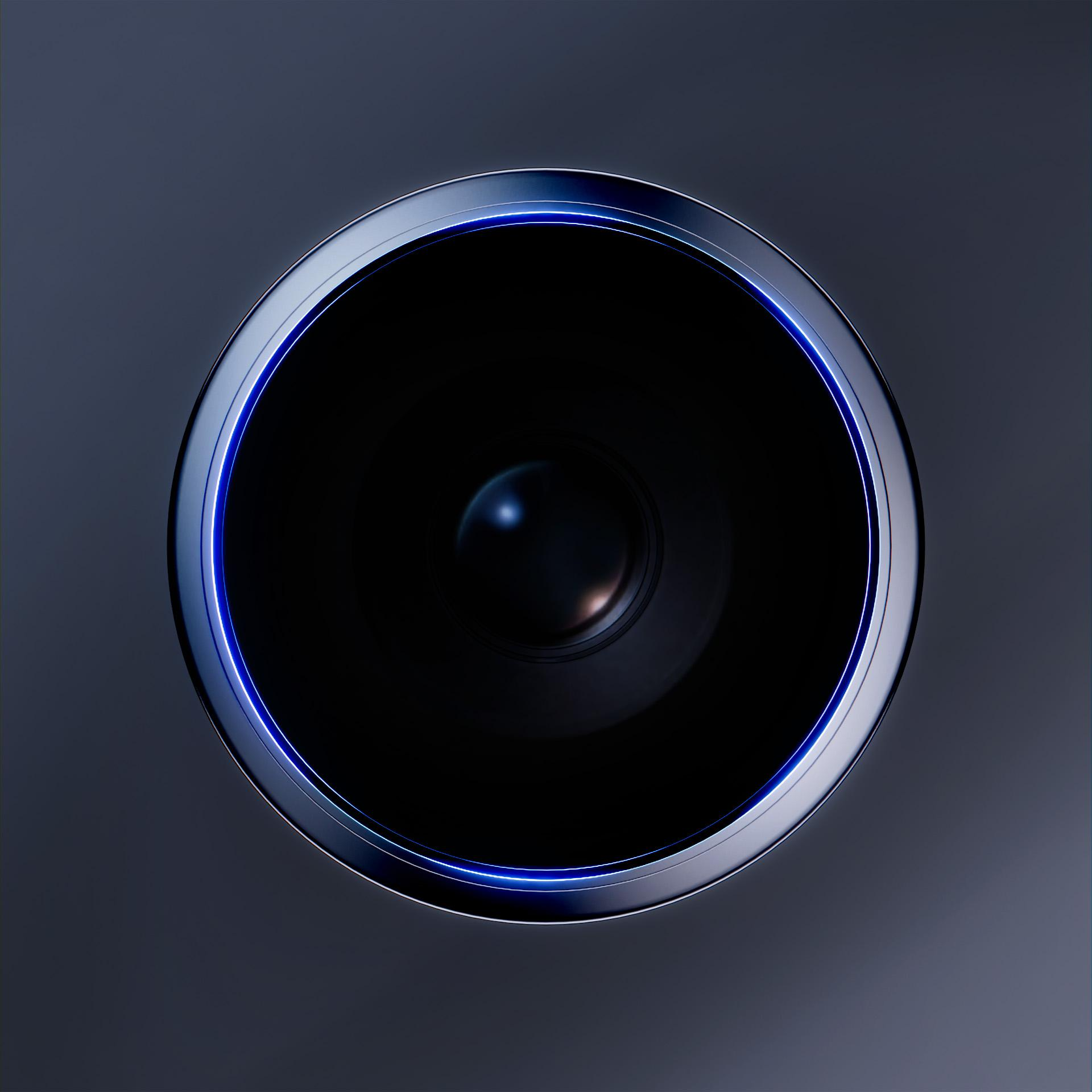 Zbliżenie okrągłego obiektu z ciemnym środkiem i srebrną obwódką z niebieskim neonem. Tło jest ciemnoszare.
