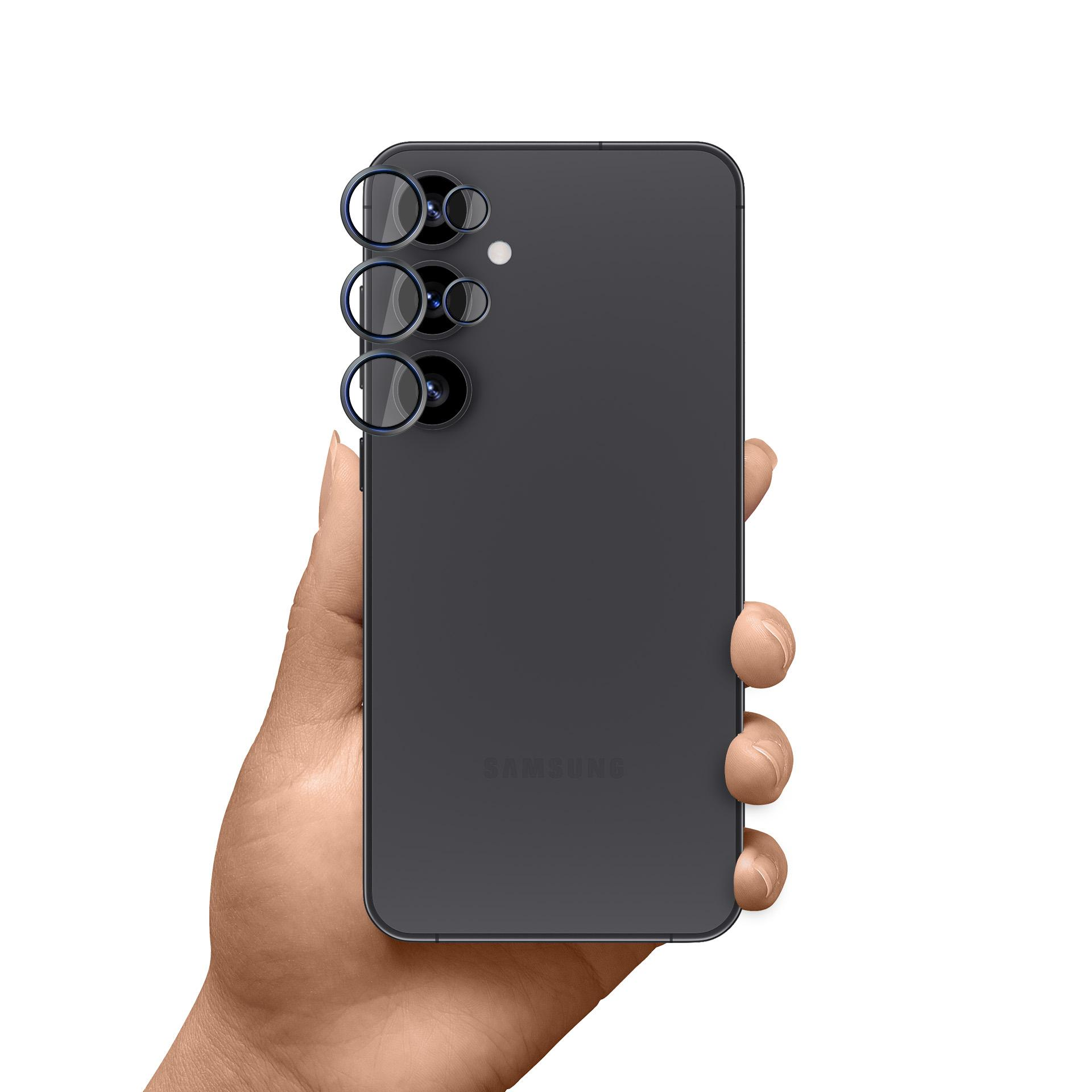 Dłoń trzymająca ciemnoszary telefon Samsung. Widoczne są tylne kamery telefonu. Tło jest białe.