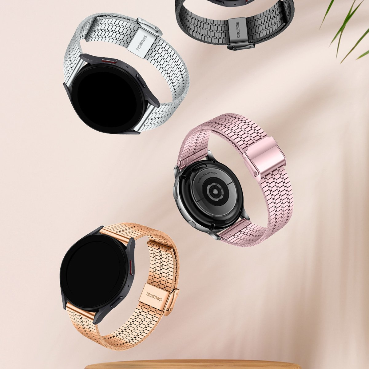 Vier Smartwatches mit Metallbändern. Silberne, schwarze, roségoldene und rosa Bänder. Der Hintergrund hat einen hellbraunen Farbverlauf.