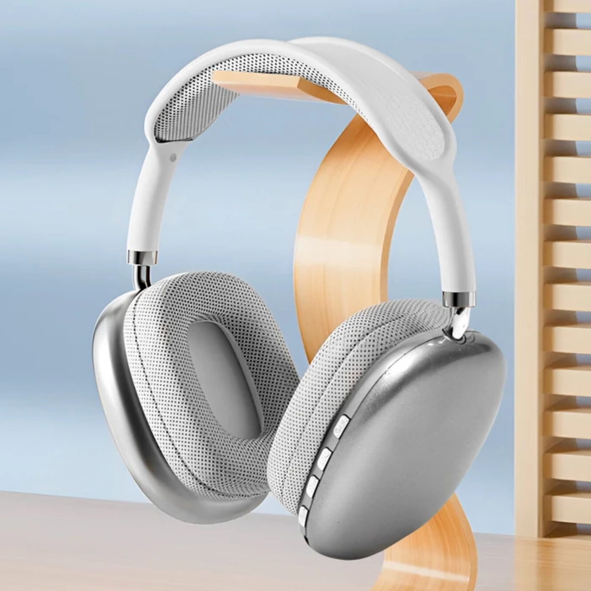Auriculares plateados en un soporte de madera. Diadema y almohadillas blancas. Fondo azul claro.