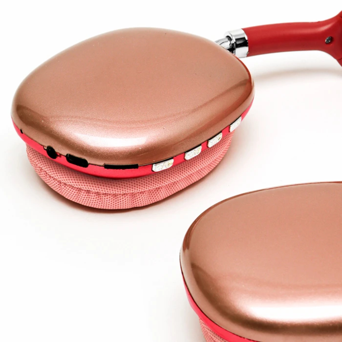 Auriculares oro rosa con detalles rojos sobre fondo blanco. Las almohadillas son rosas.