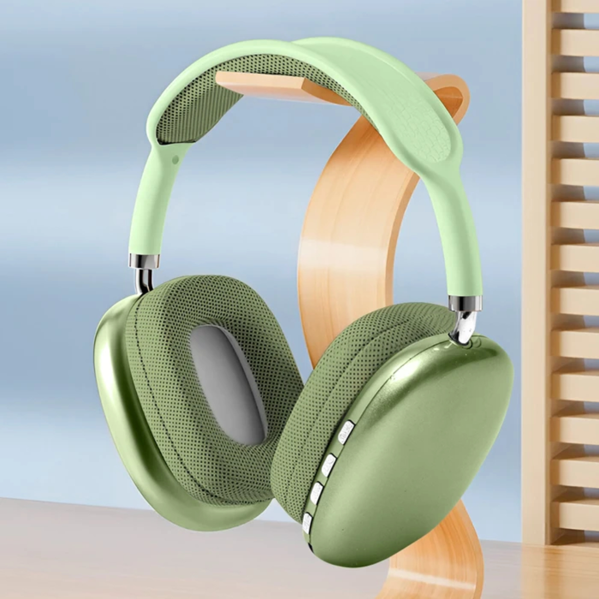 Auriculares verdes sobre un soporte de madera. Tienen almohadillas suaves y diadema acolchada. Listones de madera en el fondo.