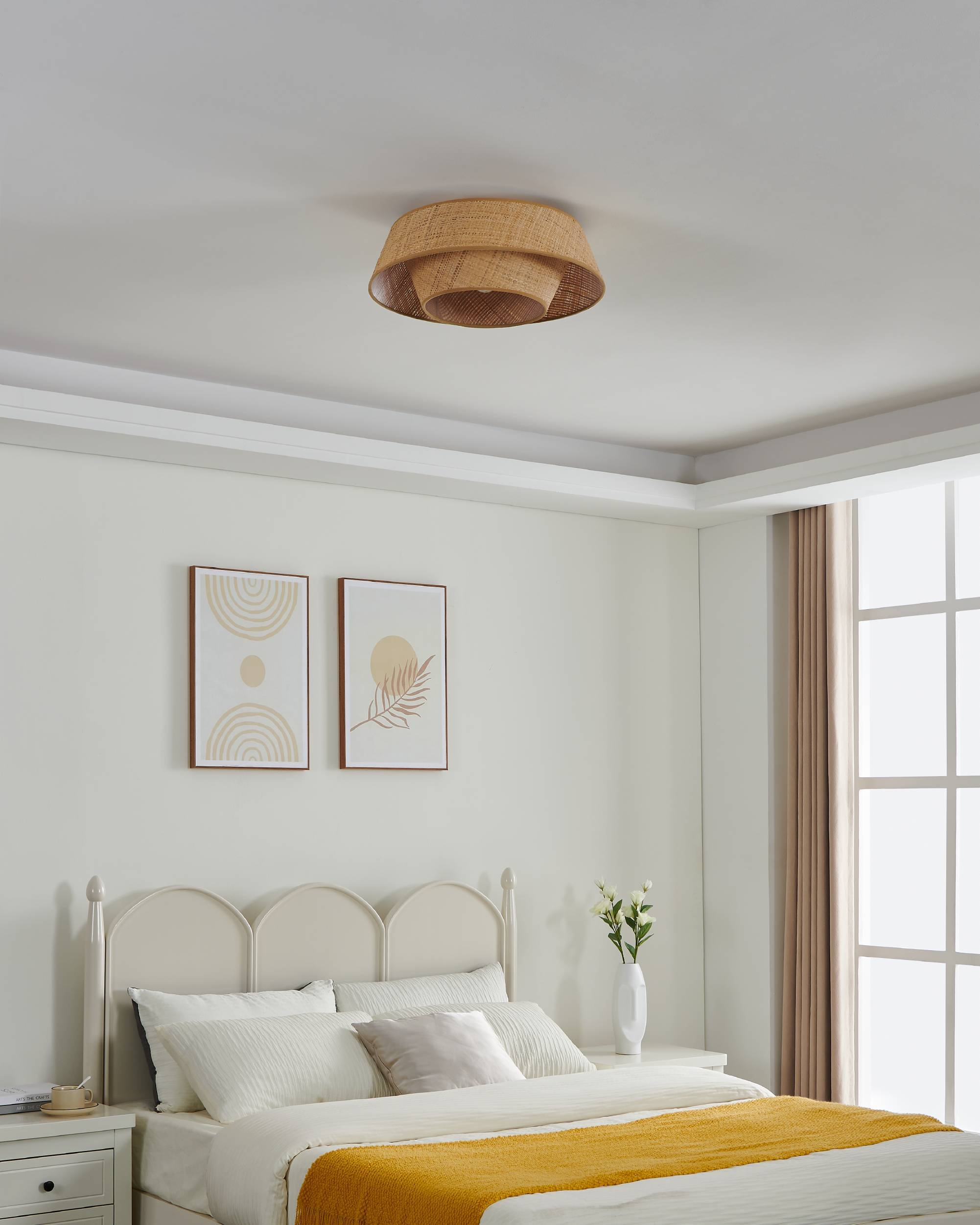 Schlafzimmer mit gewebter Deckenleuchte, Bett mit gelber Decke, Kunst und Fenster.