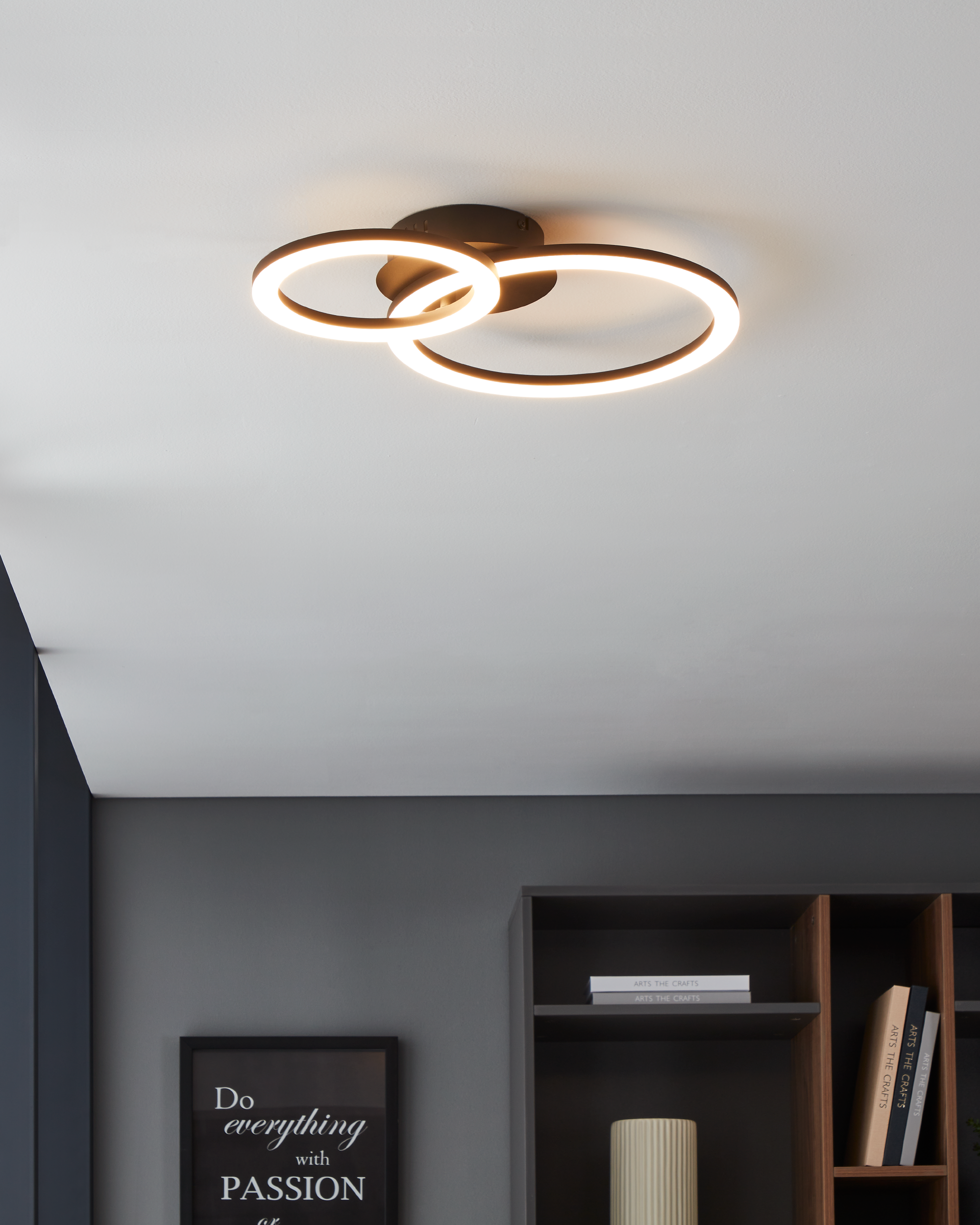 Una moderna plafoniera con due anelli luminosi sovrapposti. Cornice marrone scuro, che emette una luce bianca soffusa.