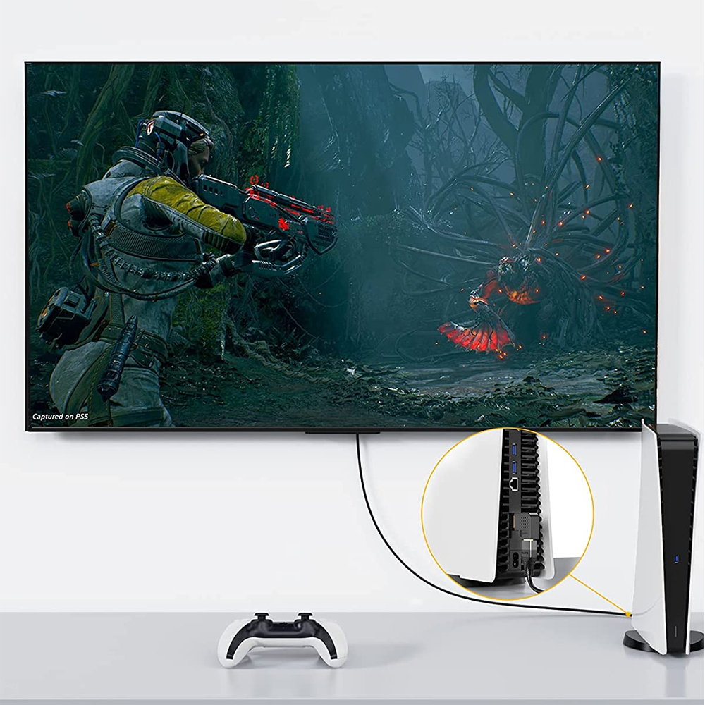 Auf einem Fernseher wird eine Spielszene gezeigt. Ein Raumanzug schießt mit einer Waffe. Konsole und Controller stehen unter dem Fernseher.
