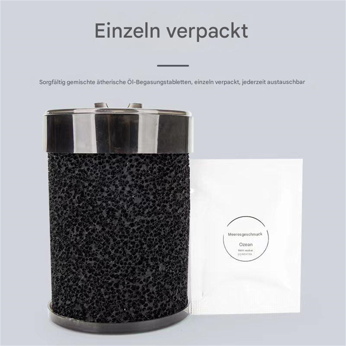 Ein schwarzes zylindrisches Objekt mit einem metallischen Deckel neben einem weißen Sachet. Hintergrund hellgrau.