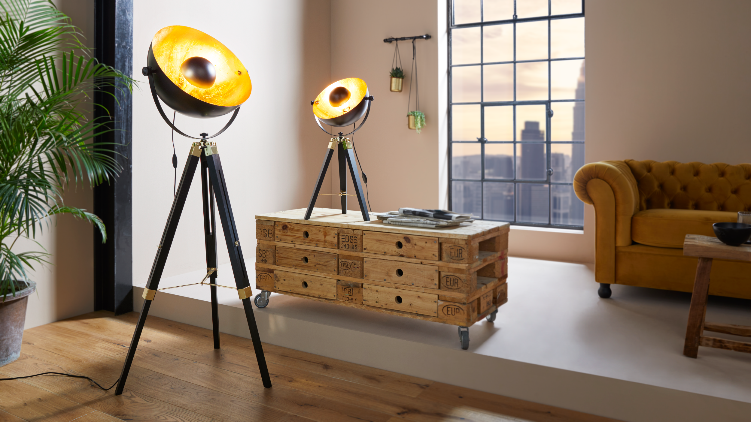 Un interior con dos lámparas, un mueble de madera, un sofá amarillo y una ventana con vistas al horizonte de la ciudad.